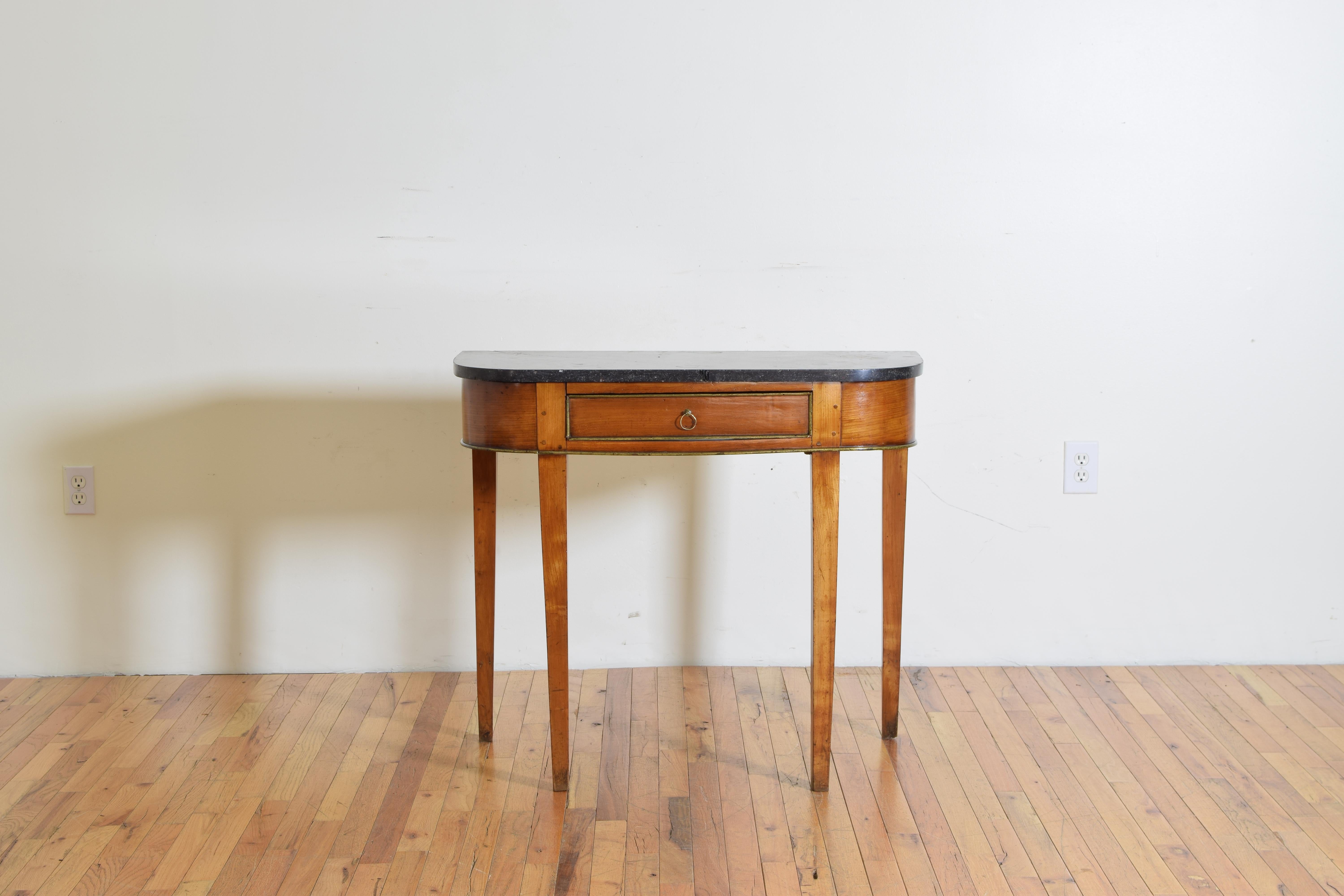 The rectangular top with rounded edges and a conforming marble top, the case housing one drawer with a brass ring pull, the drawer trimmed in brass as is the lower edge of the case, raised on square tapering legs, second quarter of the 19th century.