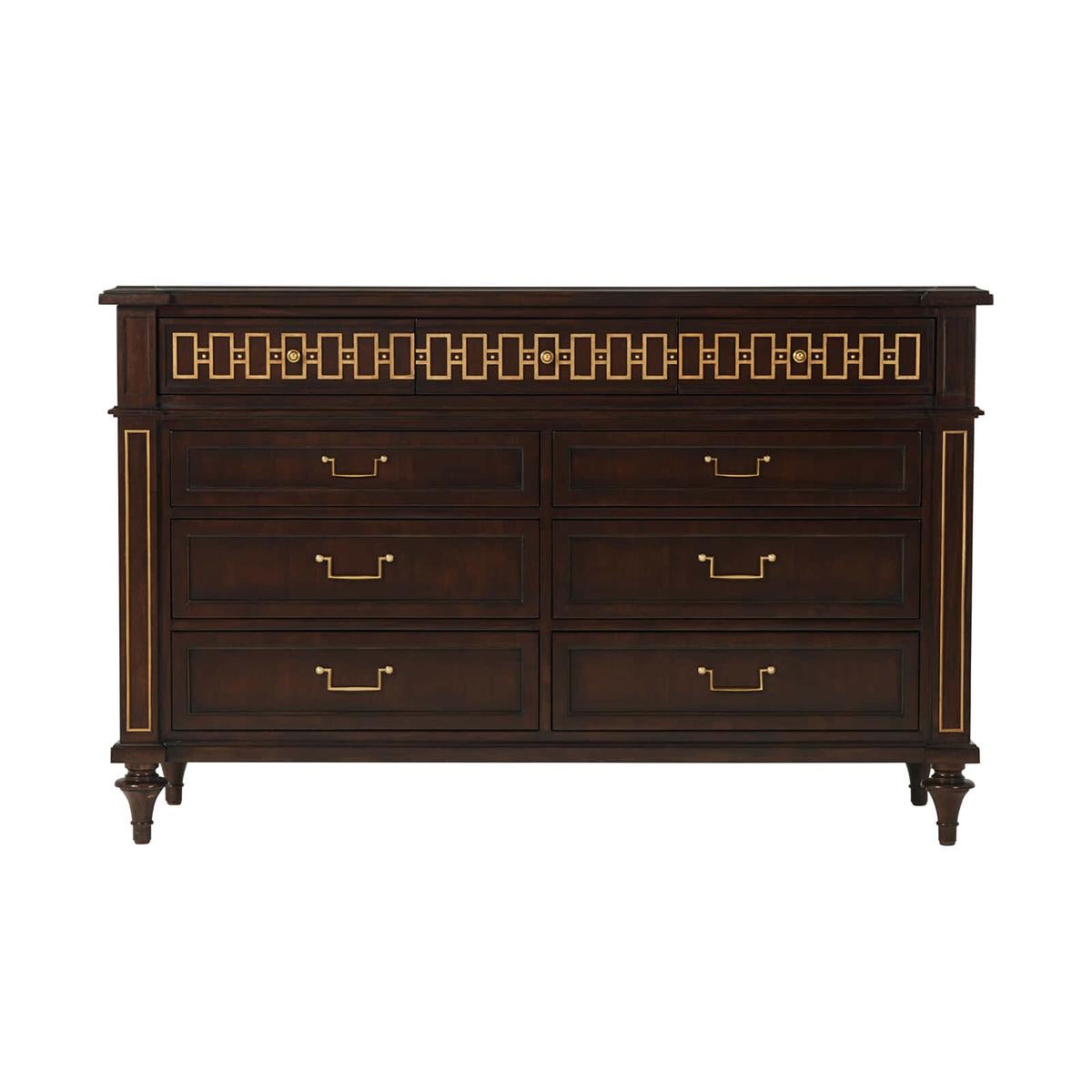 French neo classic dresser in a mahogany finish with gilded highlights. With a shaped chamfered edge top with a relief decorated three drawer freize, above six generously sized paneled drawers. With brass bail handles raised on turned toupee