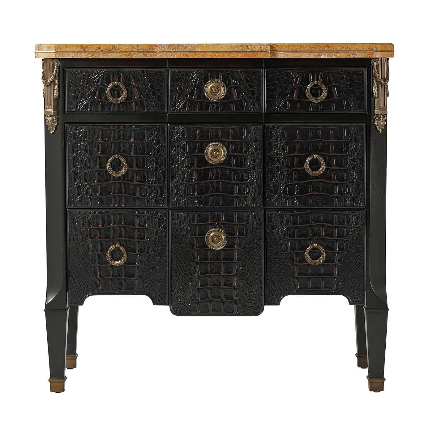A French neo classic marble top commode small ebonised and Kalahari chest of drawers, the Sahara marble top with brass inlaid edges, above three drawers with brass handles, the canted angles with brass column capitals above square tapering legs. The