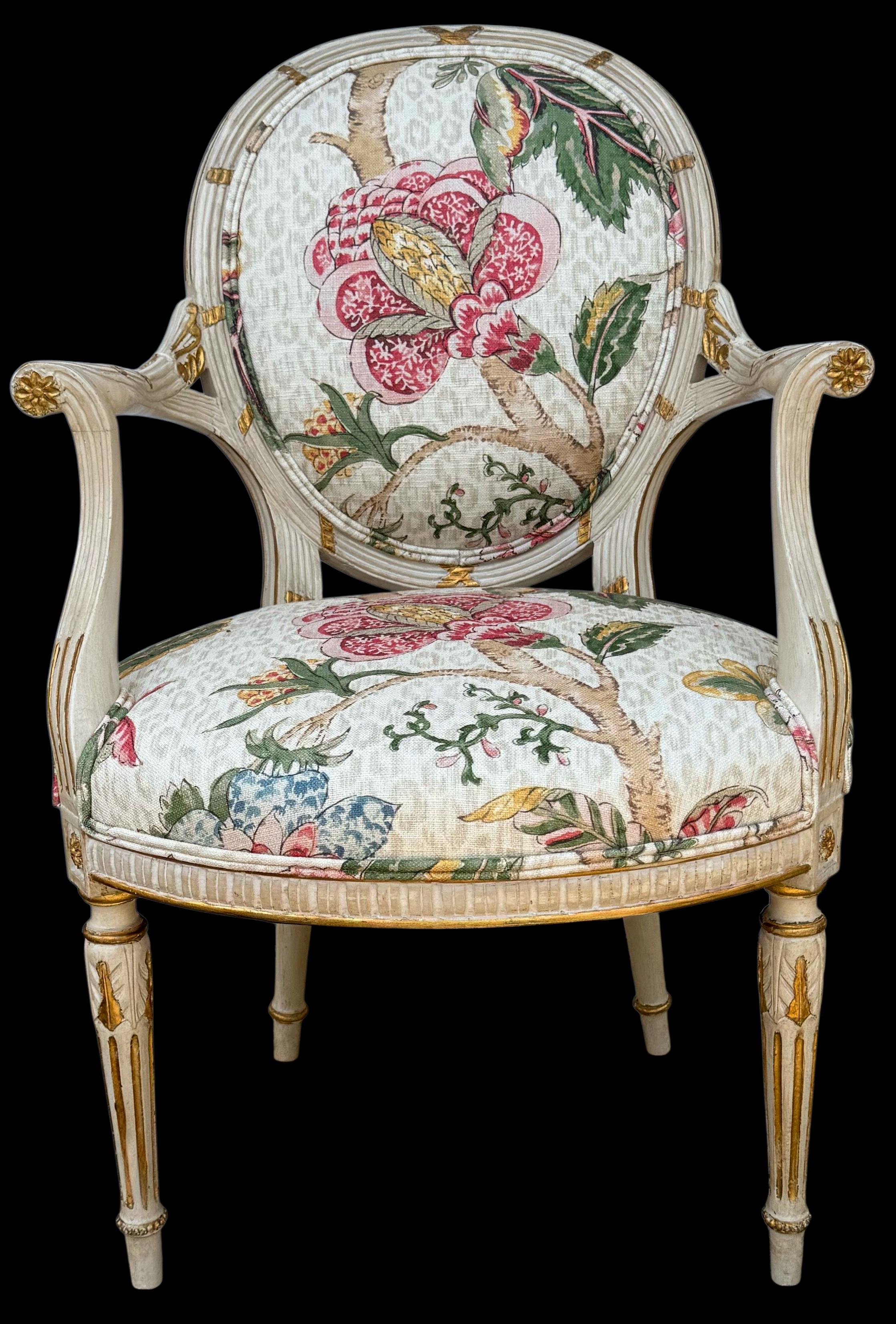This is a lovely neo-classical style arm chair with an ivory painted frame and gilt accents. The vibrant floral upholstery has a neutral leopard background. The frame has some minor wear.