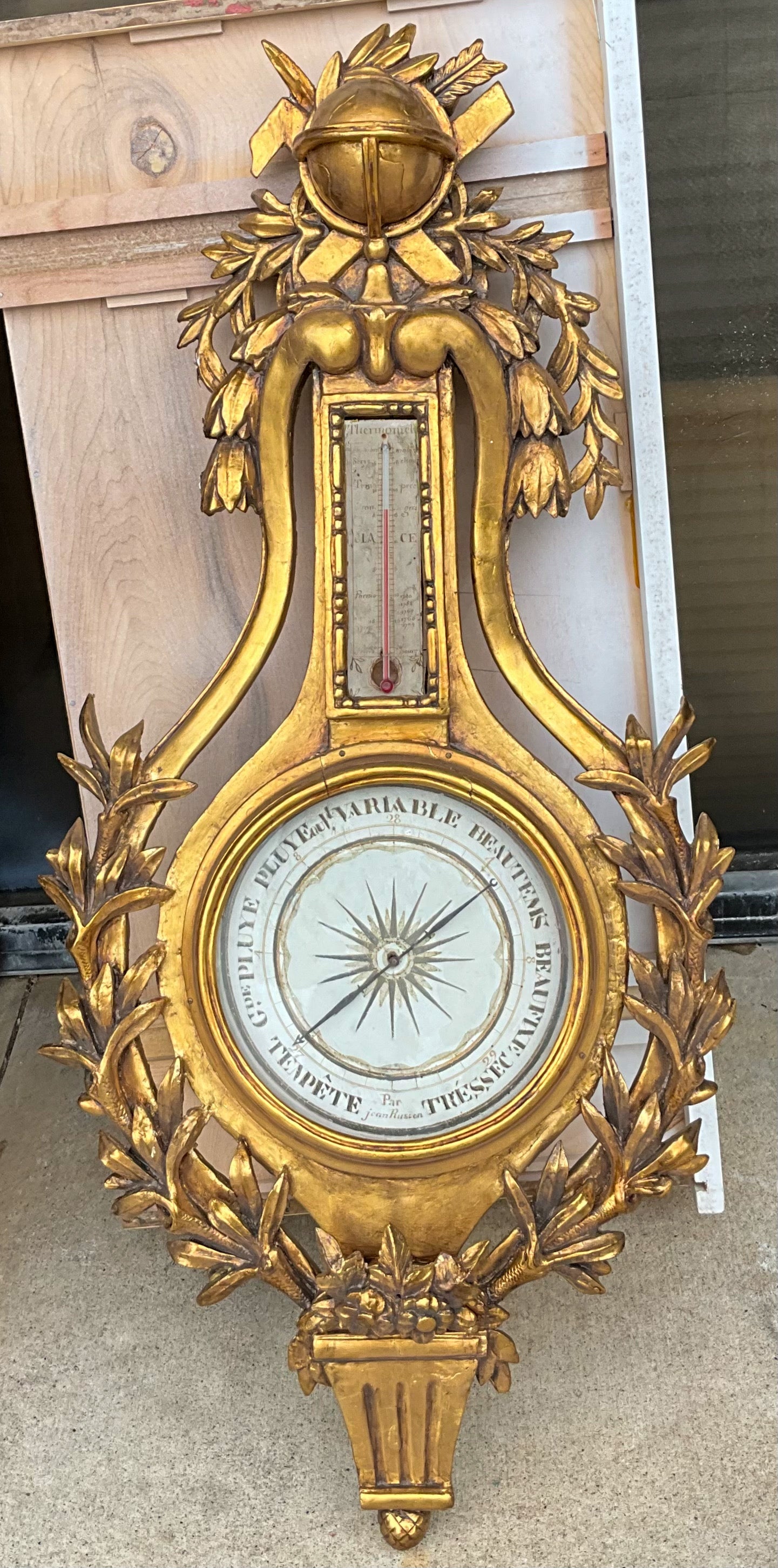 This is amazing! It is a 19th century French Louis XVI style carved giltwood barometer. The crest appears to be a carved armillary of some sort with cascading laurel leaves and branches. It appears to be signed. Antique condition with a beautiful