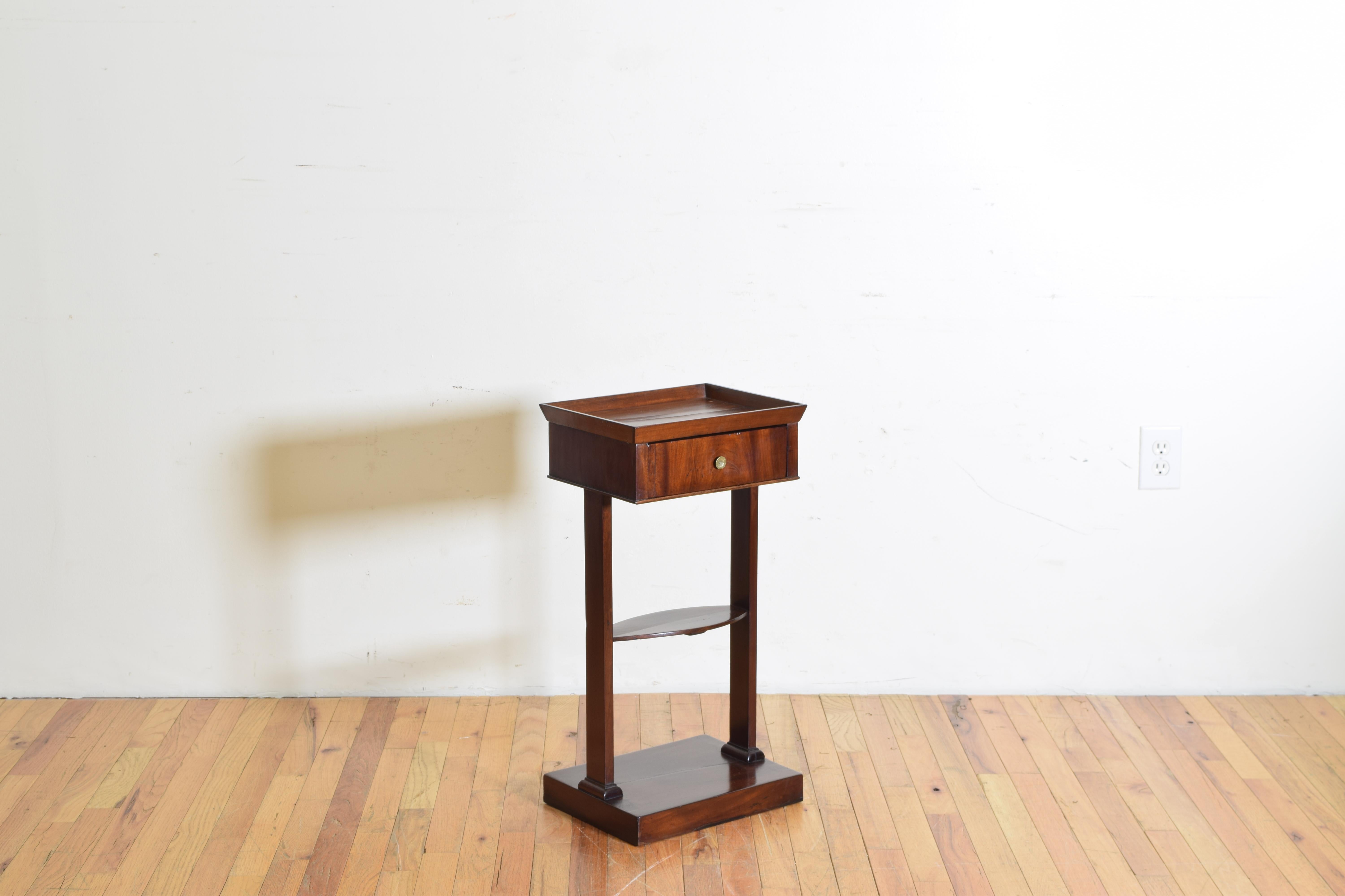 Somewhat diminuitive in size this table features a tray top with a two-way drawer raised on straight trestle legs joined in the middle by a flattened oval stretcher, the legs continuing to a square platform base, second quarter of the 19th century.