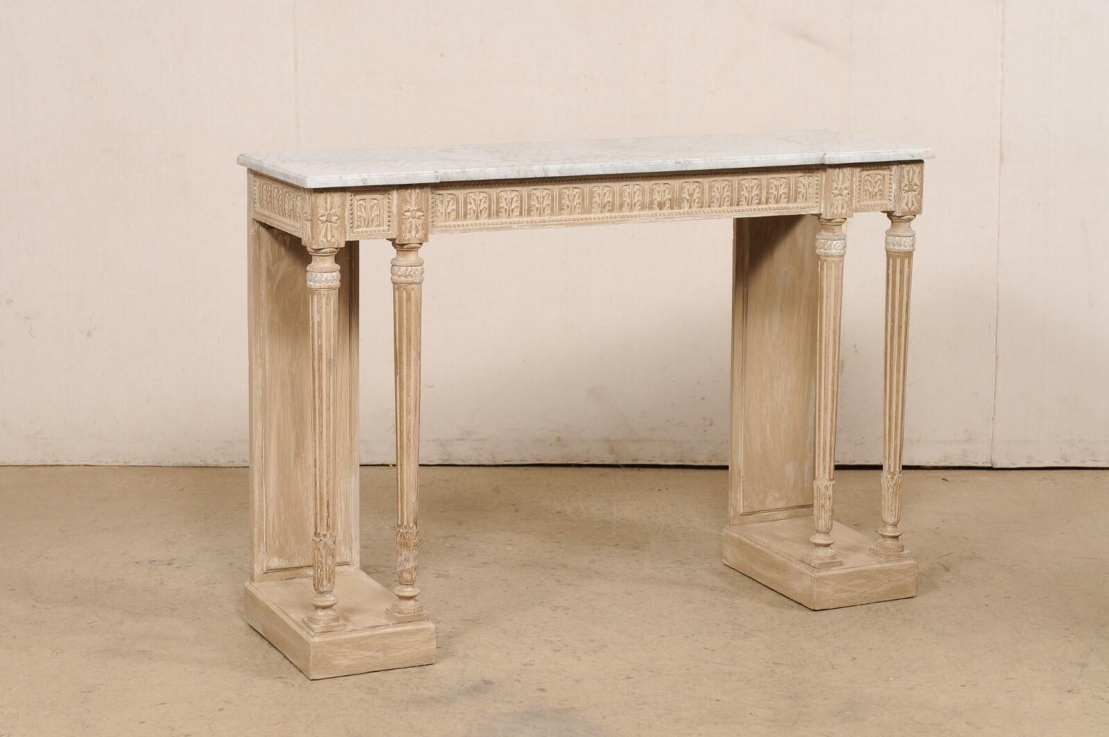 A French carved-wood console table with its original marble top, from the 19th century. This antique table from France features a slender, rectangular-shaped white/grey marble top, with a subtle reverse breakfront design at front, which rests upon
