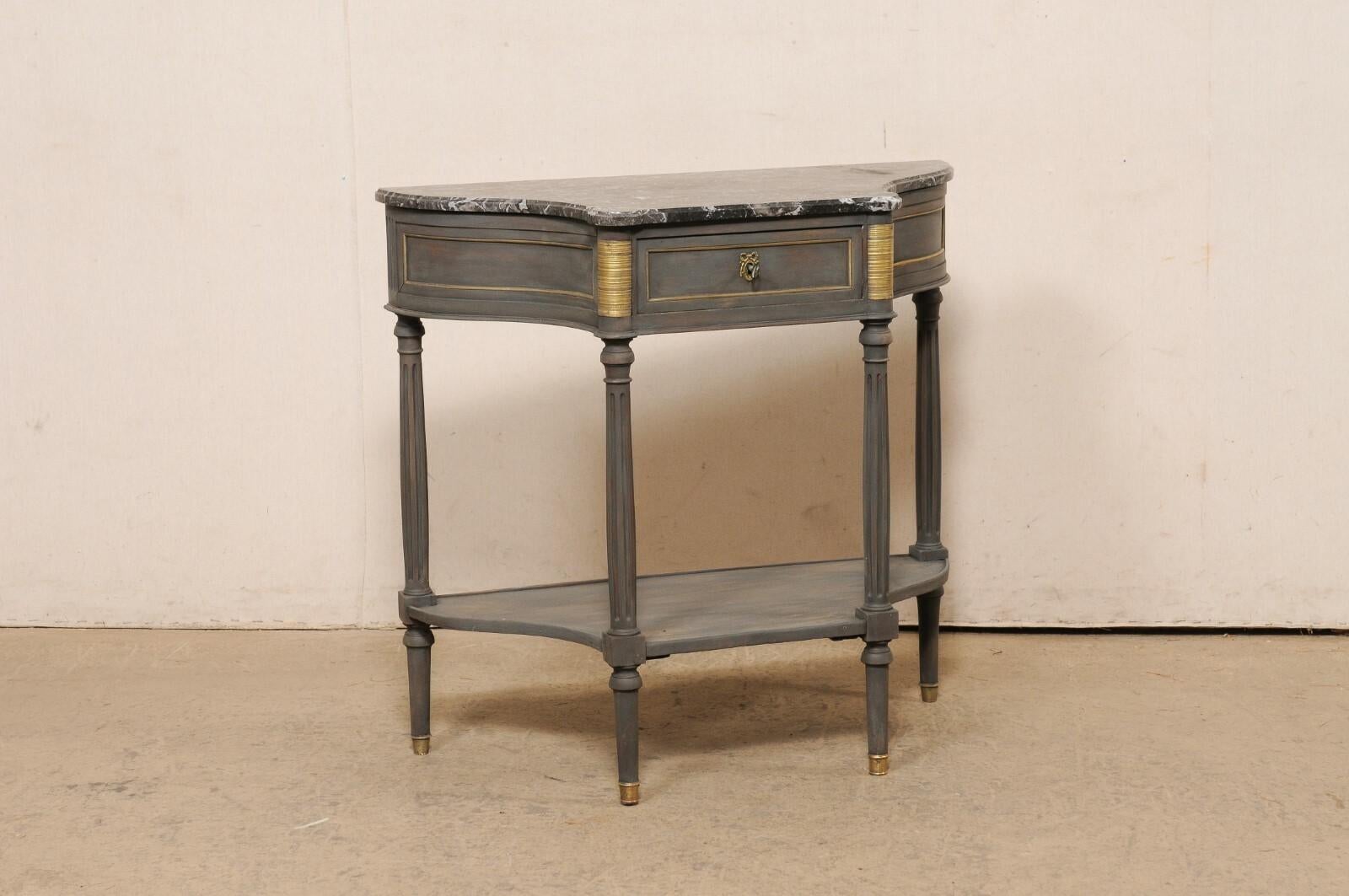 A French Neoclassical carved and painted wood demi lune console, with marble top and brass accents, from the 19th century. This antique table from France has a black marble top (with gray and white veining), with demi-style shape as the rear/wall
