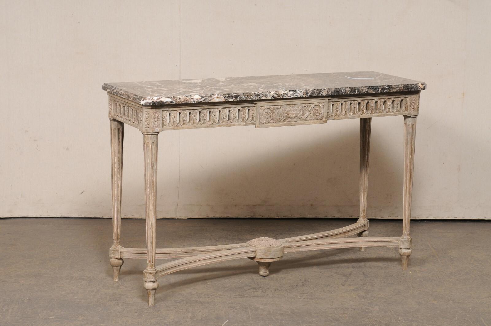 A French Neoclassical style carved-wood console table with marble top, circa 1960's. This vintage table from Italy has been designed with lovely Neoclassic touches throughout and features a rectangular-shaped marble top above a pierce-carved apron