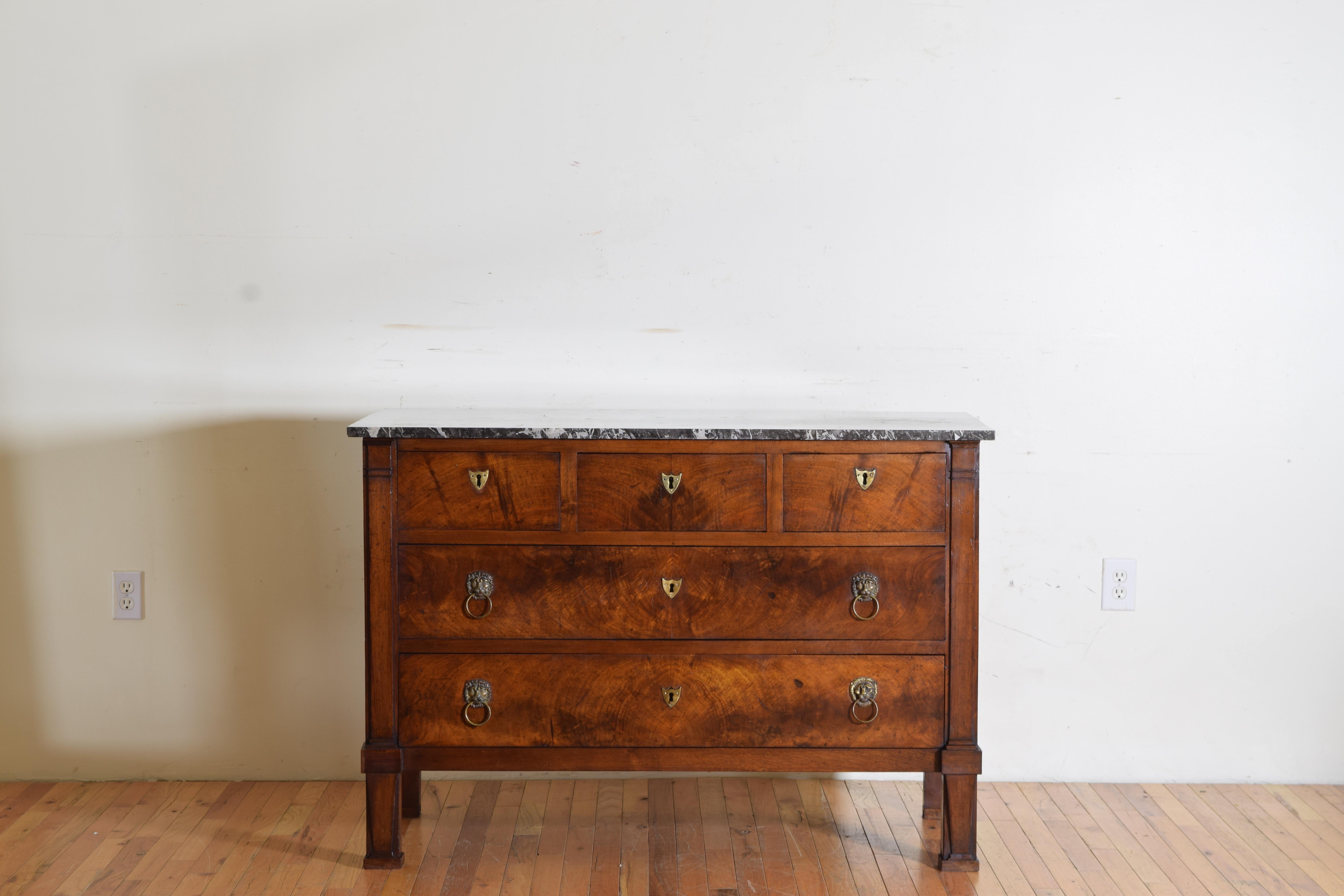 Having a dark grey and white veined marble top atop a conforming case housing three upper drawers over two larger lower drawers, all retaining original locks, the drawers with brass escutcheons and lion mask pulls, flanked by pilasters terminating