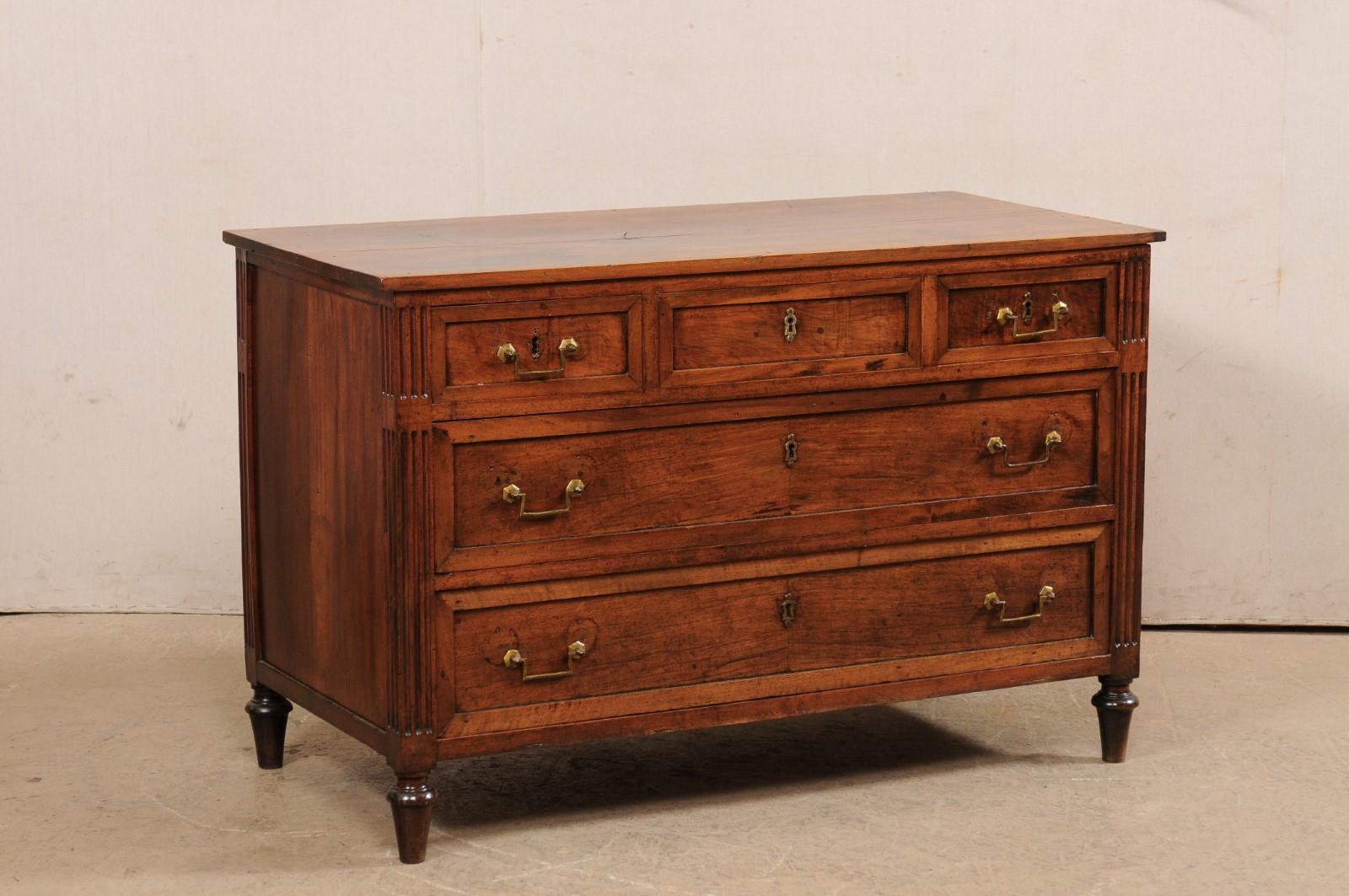 A French neoclassical style carved walnut chest of drawers from the mid 19th century. This antique commode from France features a rectangular-shaped top, above a neoclassical case which houses three small-sized drawers set horizontally over a pair