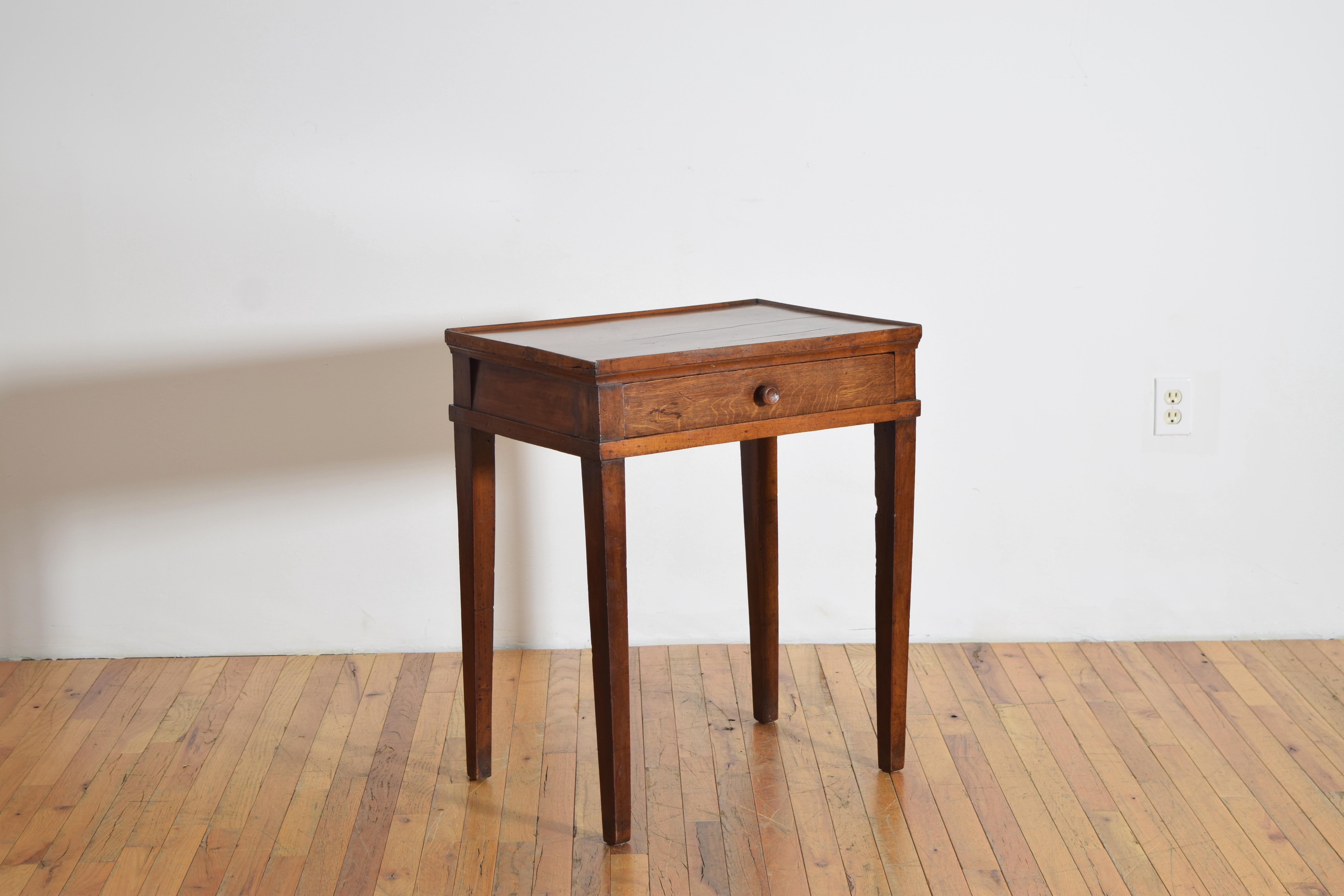 having a rectangular top with a raised gallery edge, the case housing one oak drawer with turned wooden pull, raised on square slightly tapering legs