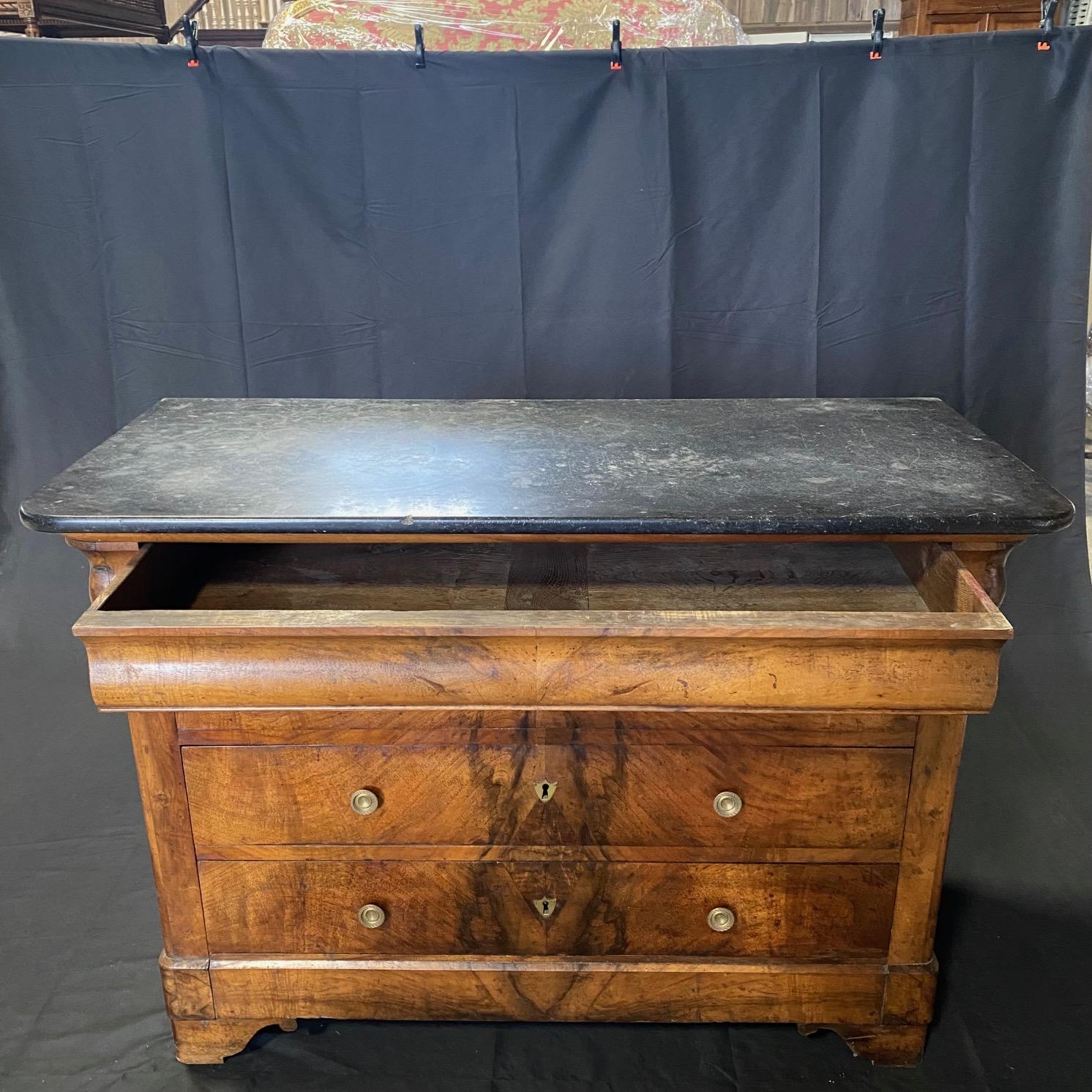 A French Neoclassical commode, with marble top and exquisite brass accent knobs, from the 19th century. This antique chest from France features a rectangular-shaped gray marble top, over case which houses four drawers (upper drawer is disguised