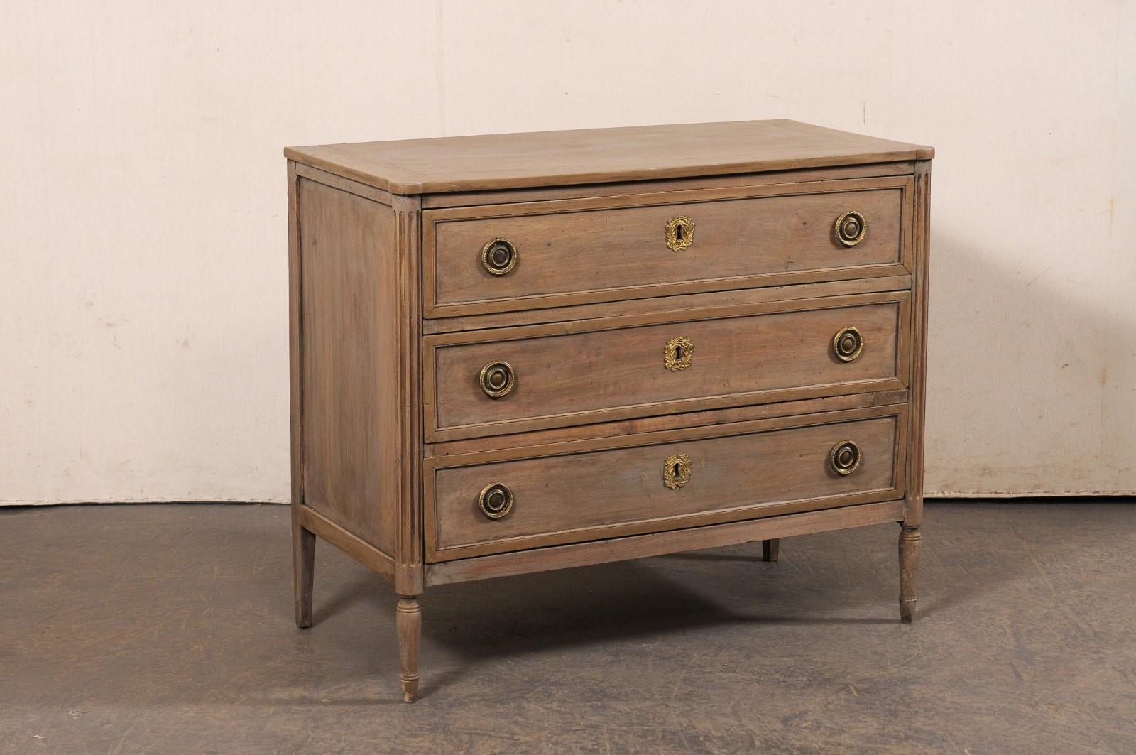 Una commode francese neoclassica in legno intagliato del XIX secolo. Questo antico cassettone francese presenta un piano di forma rettangolare con angoli frontali pronunciati e arrotondati verso l'esterno, in cima a una cassa dal design neoclassico