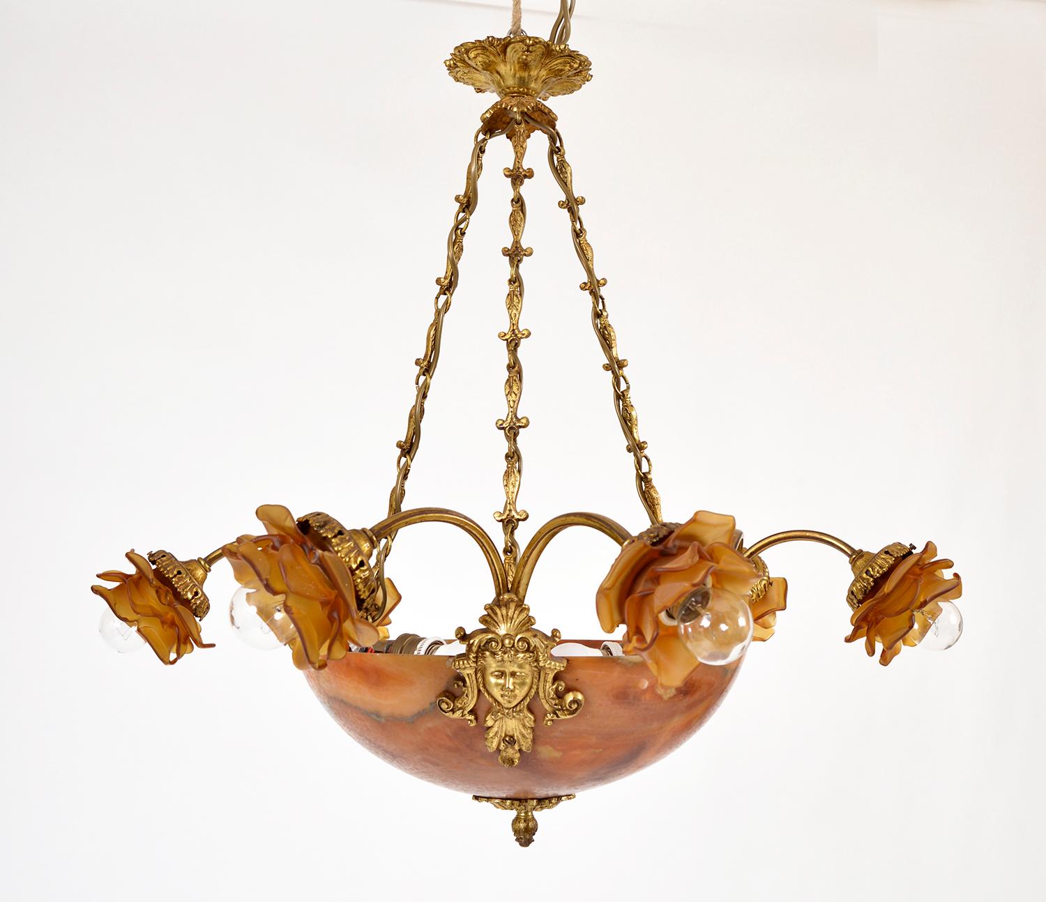 A stunning early 20th century amber alabaster chandelier on chains, featuring three highly decorative ormolu faces, from which stem six brass arms terminating in amber glass roses. The dark veined figuring in the rouge alabaster bowl is wonderful,