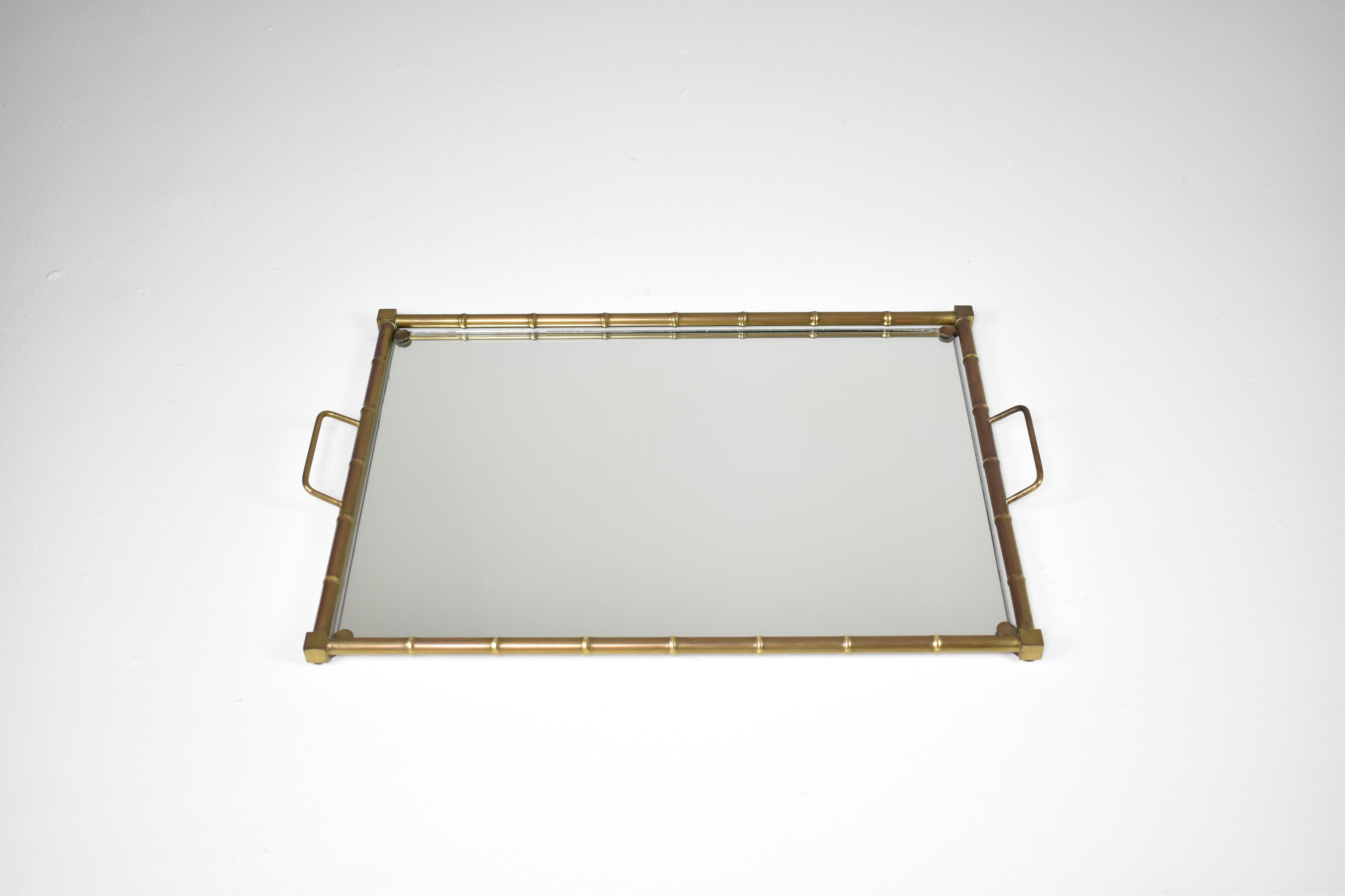 Un elegante vassoio della metà del XX secolo in stile Hollywood Regency con raffinati dettagli in ottone ispirati al bambù. Realizzato in ottone massiccio, con una patina naturale che aggiunge carattere. Perfetto per servire, esporre oggetti
