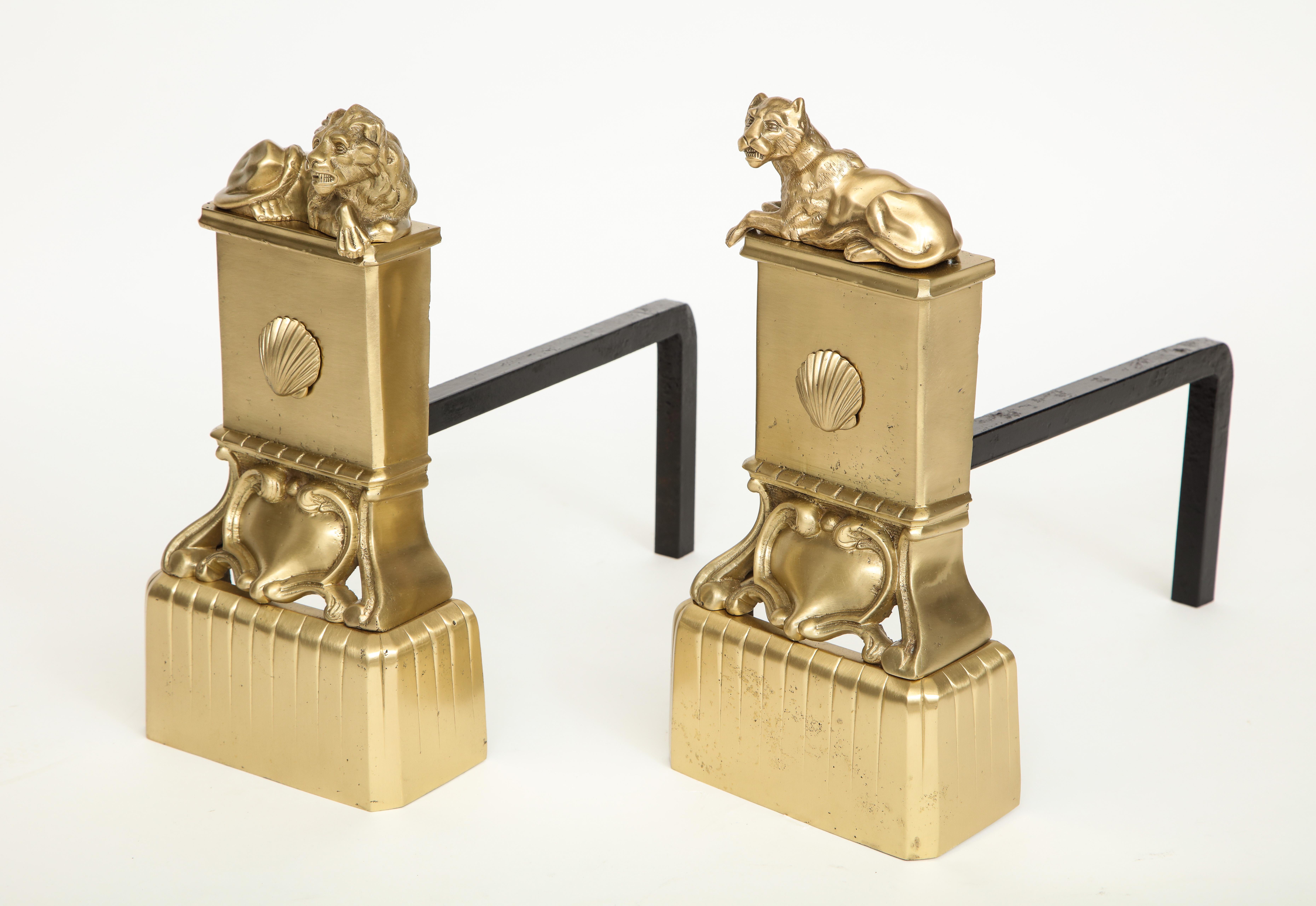 Pair of French satin brass andirons with male and female stylized lions in repose, iron backs.