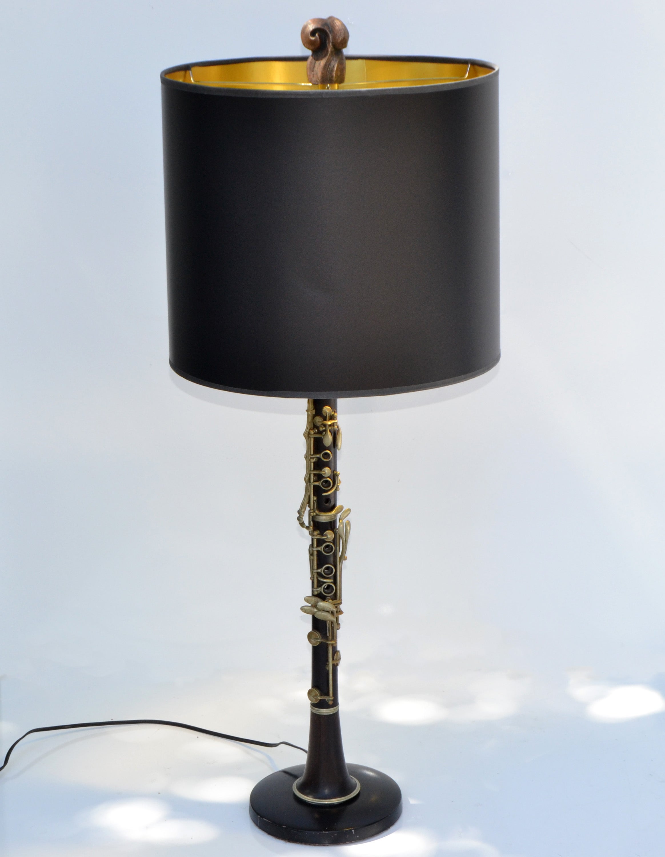 Neoclassical rosewood & brass clarinet table lamp mounted on a round metal base made in France.
Comes with harp and carved gilt wood finial and custom made black & gold drum shade.
Felt cover underneath the base to protect Your wood Furniture.