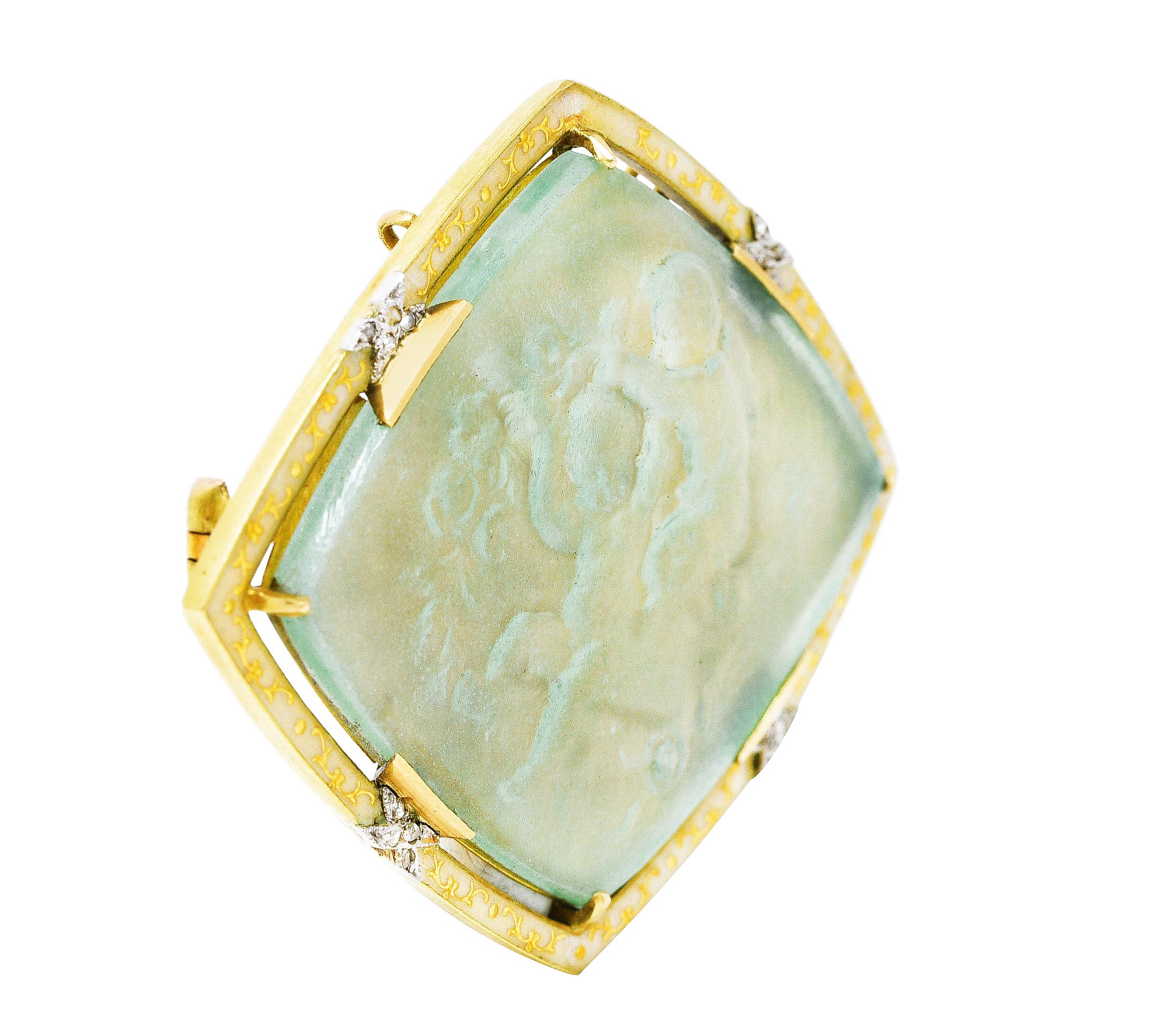 Brooch centers a rhombus shaped glass cameo depicting two winged cherubs playing with a garland of flowers. Transparent blueish green in color - set by wide prongs with a gold scroll motif and enamel surround. Guilloche and transparent light yellow