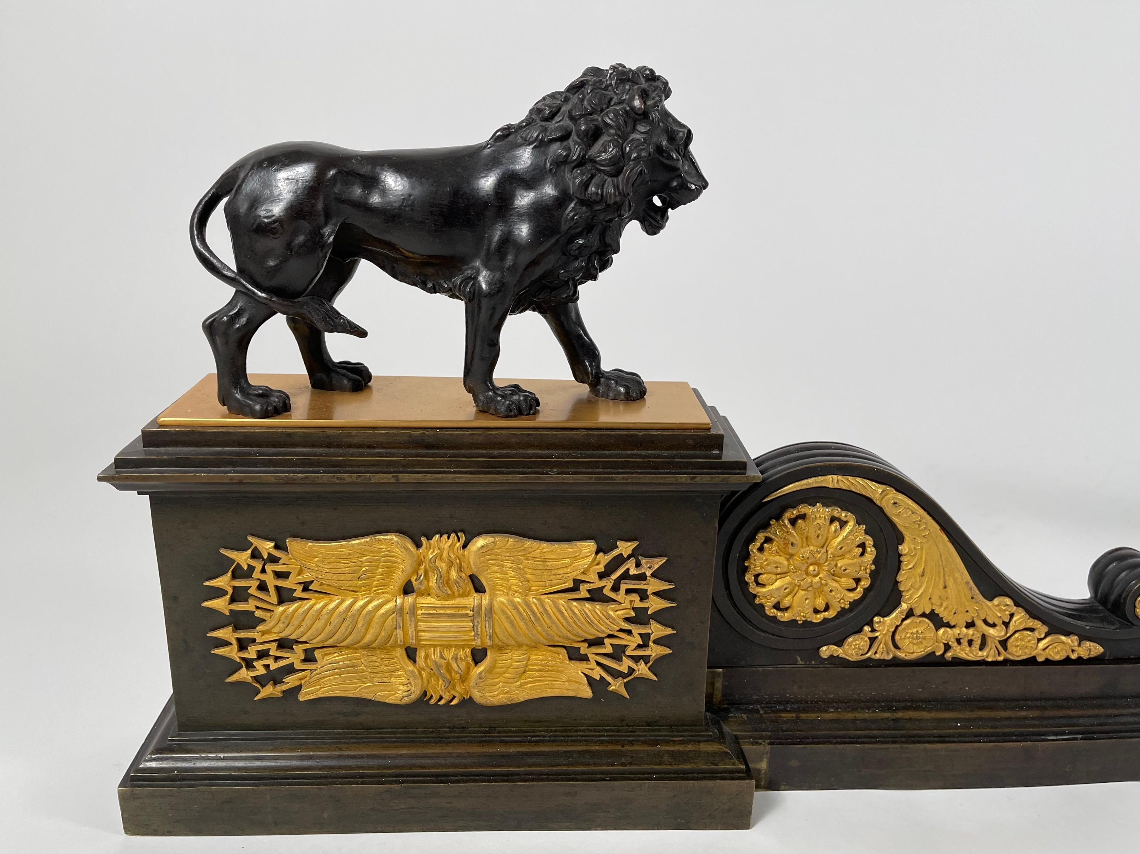 A French Neoclassical Empire period gilt bronze fireplace fender,  adjustable width, with beautifully modeled striding bronze lions on rectangular plinths with scrolls or volutes, decorated with applied finely cast ormolu Napoleonic ornamental