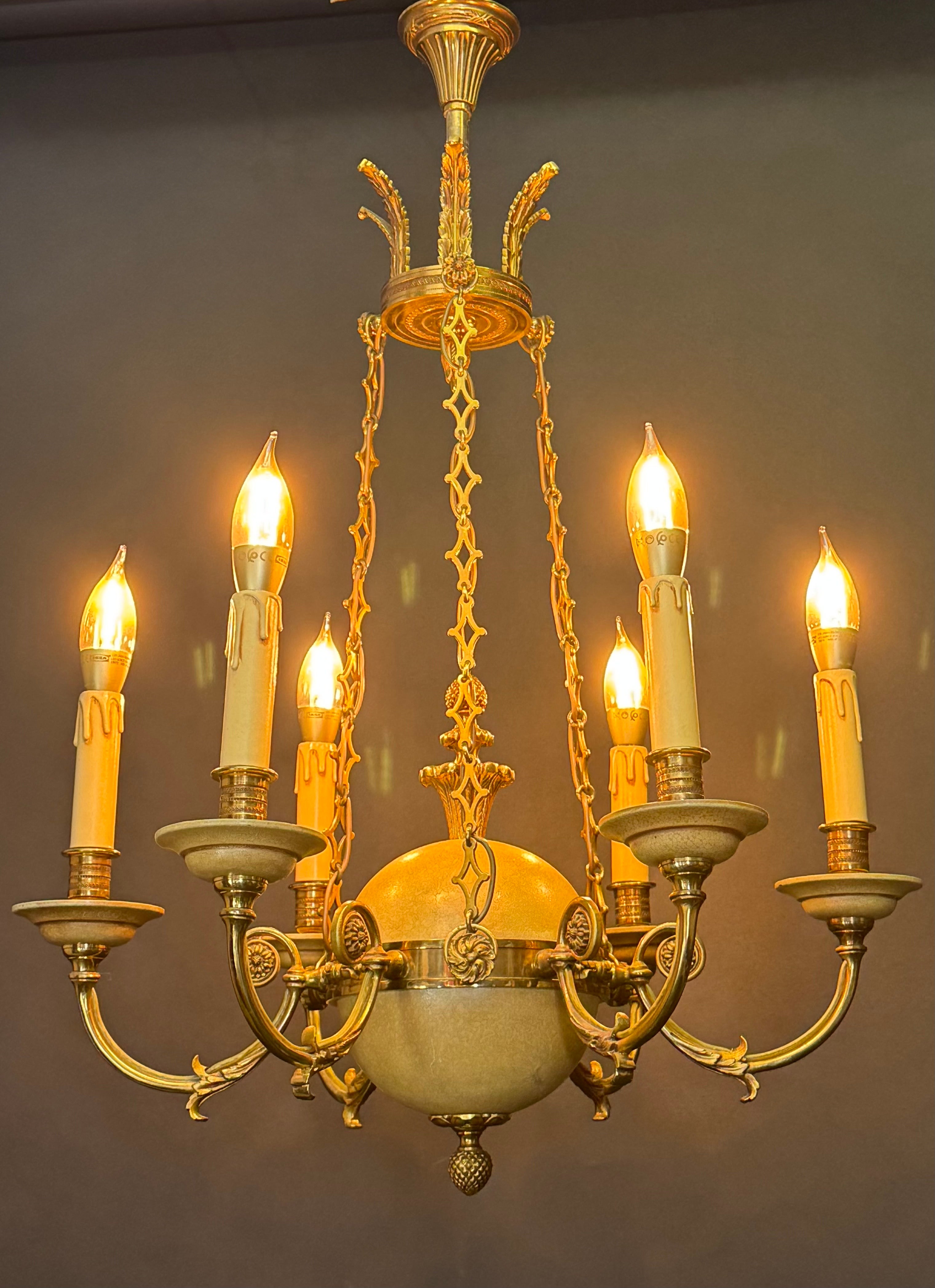 Un sorprendente lampadario neoclassico francese in stile Impero, caratterizzato da sei bracci curvi che si irradiano da un corpo sferico centrale con una splendida finitura laccata crepla in calde tonalità dorate. Il lampadario è sospeso da sei