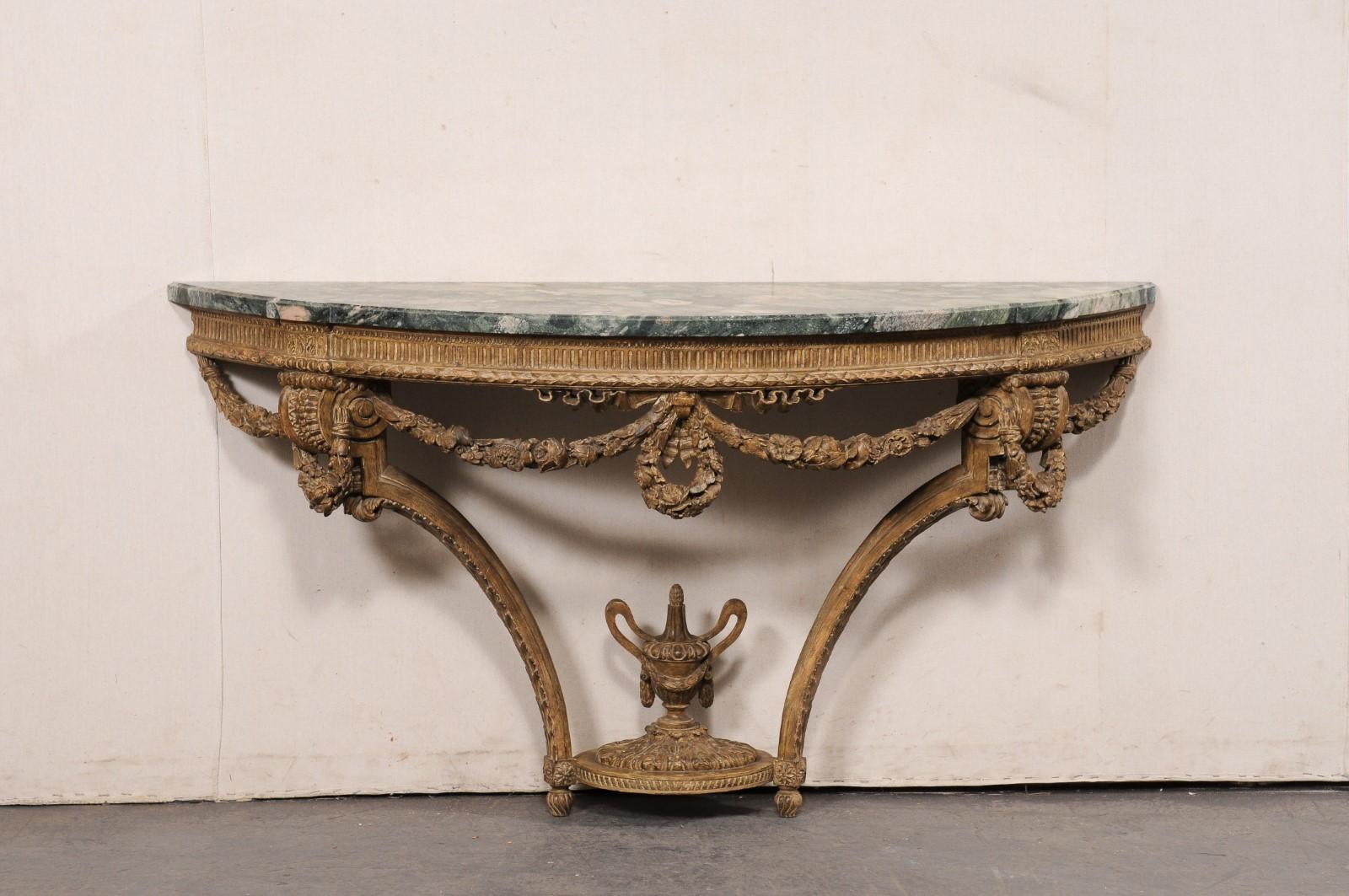 A French Neoclassical carved-wood console with marble top, from the 19th century. This antique table from France has an oblong demi-shaped (half-round) marble top with flattened backside, and a pair of shallow rectangular projections at either front