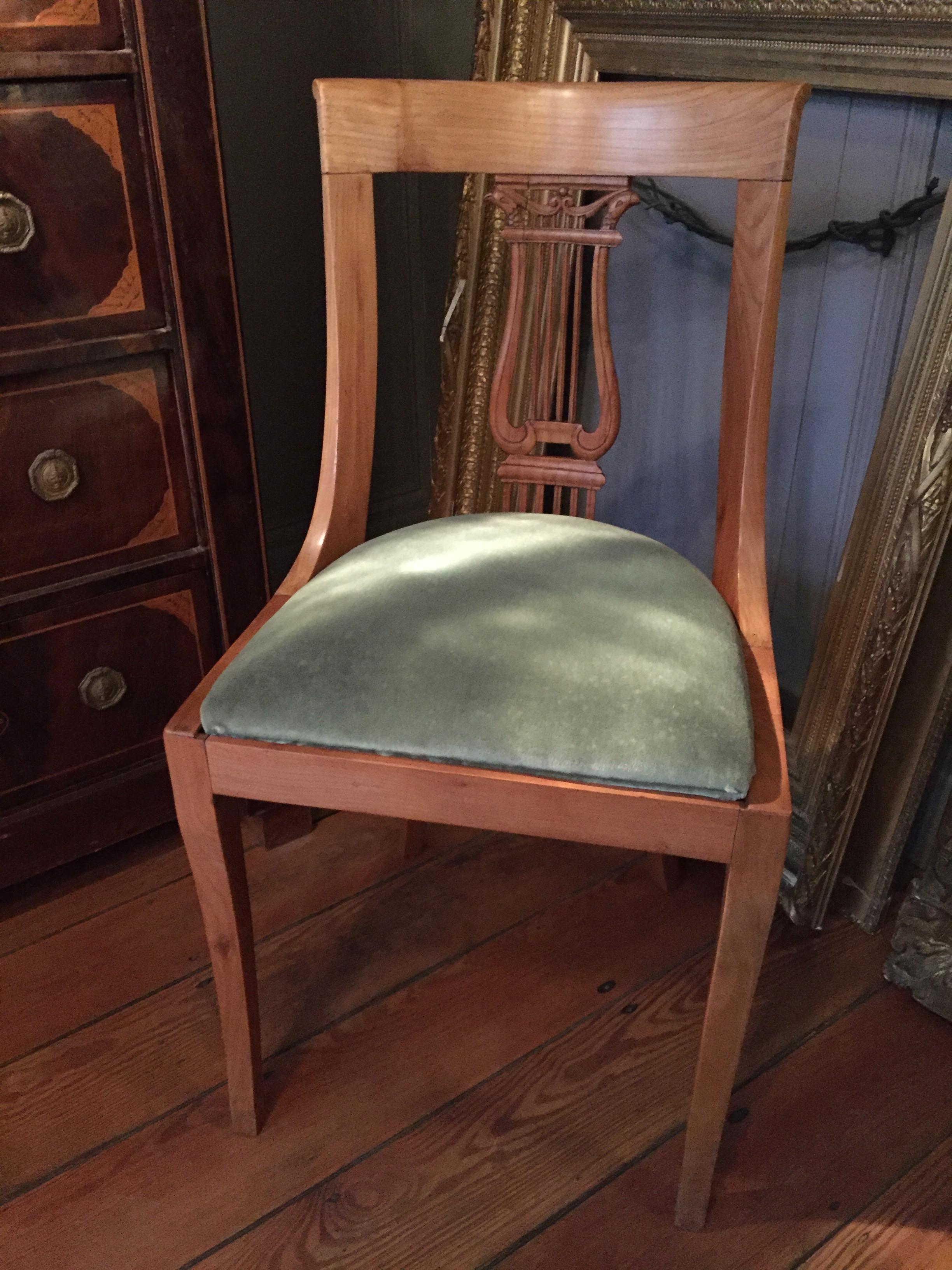 French neoclassical chairs with lyre shaped backs decorated with carved falcon heads. The chairs have a slight Klismos design attributed to the classical style of ancient Greece so popular in the neoclassical period. The concave sway backs add to