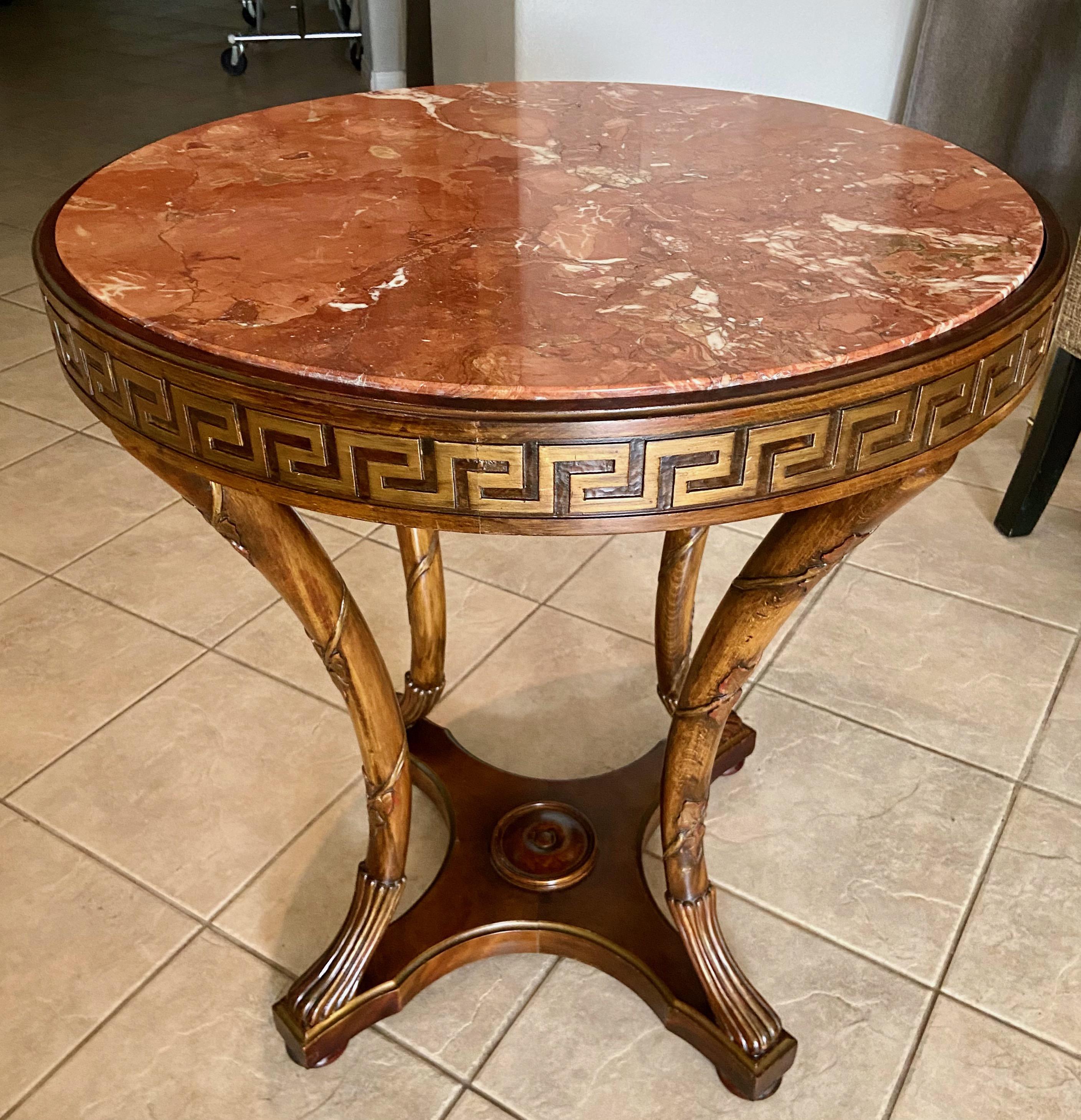 French neoclassical style round 4 leg lacquered wood gueridon or side table with inset marble top. The table has nice detailing throughout including a circular greek key carved boarder, and is supported by 4 curved saber paw footed legs decorated