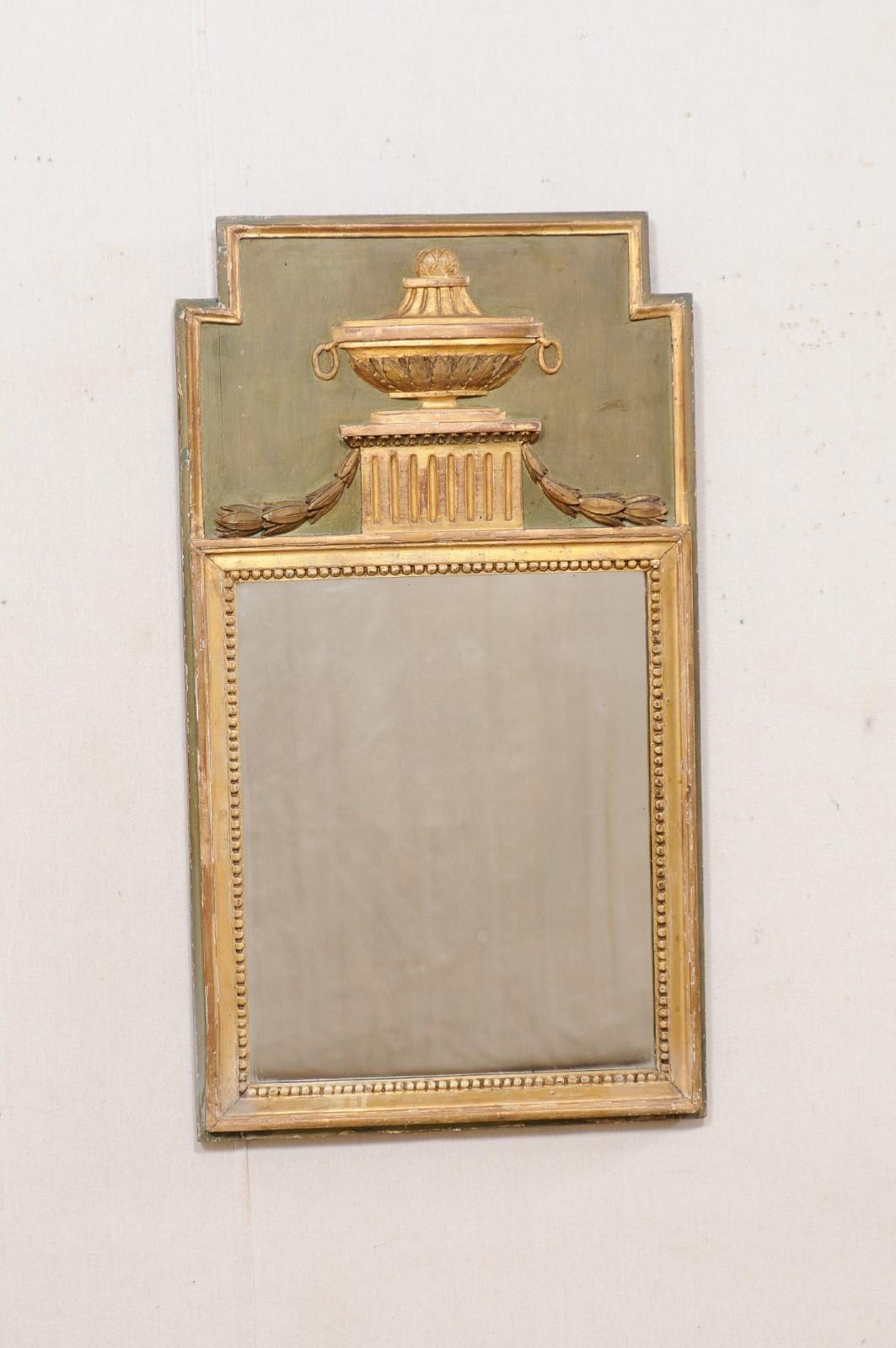 A French neoclassical mirror, with its original finish, from the early 19th century. This antique mirror from France has a mostly rectangular-shape, with step up style top crest. The carved-wood plaque top, reminiscent of trumeau design, is carved