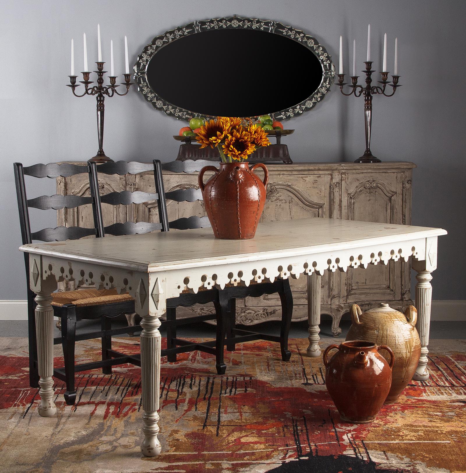 A vintage French country neoclassical style distressed painted dining table in oak, circa 1960. Heavy oak construction with lots of extra details. Carved decorative apron with fleur-de-lis motif, thick baluster style legs with fluting, and raised