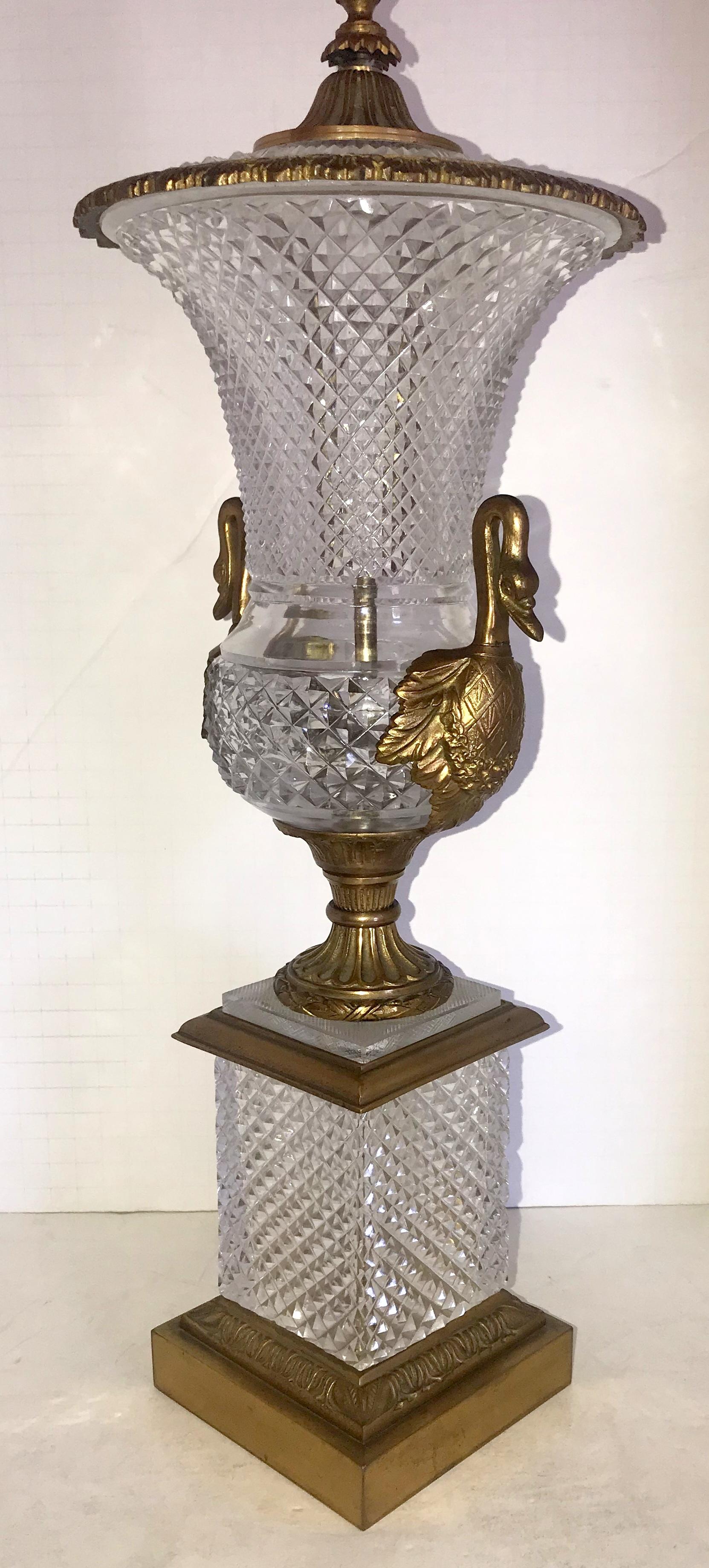 A wonderful French neoclassical pair of gilt bronze and diamond cut crystal empire ormolu mounted urns with swan handles. These beautiful urns can very easily be converted to lamps at your request.