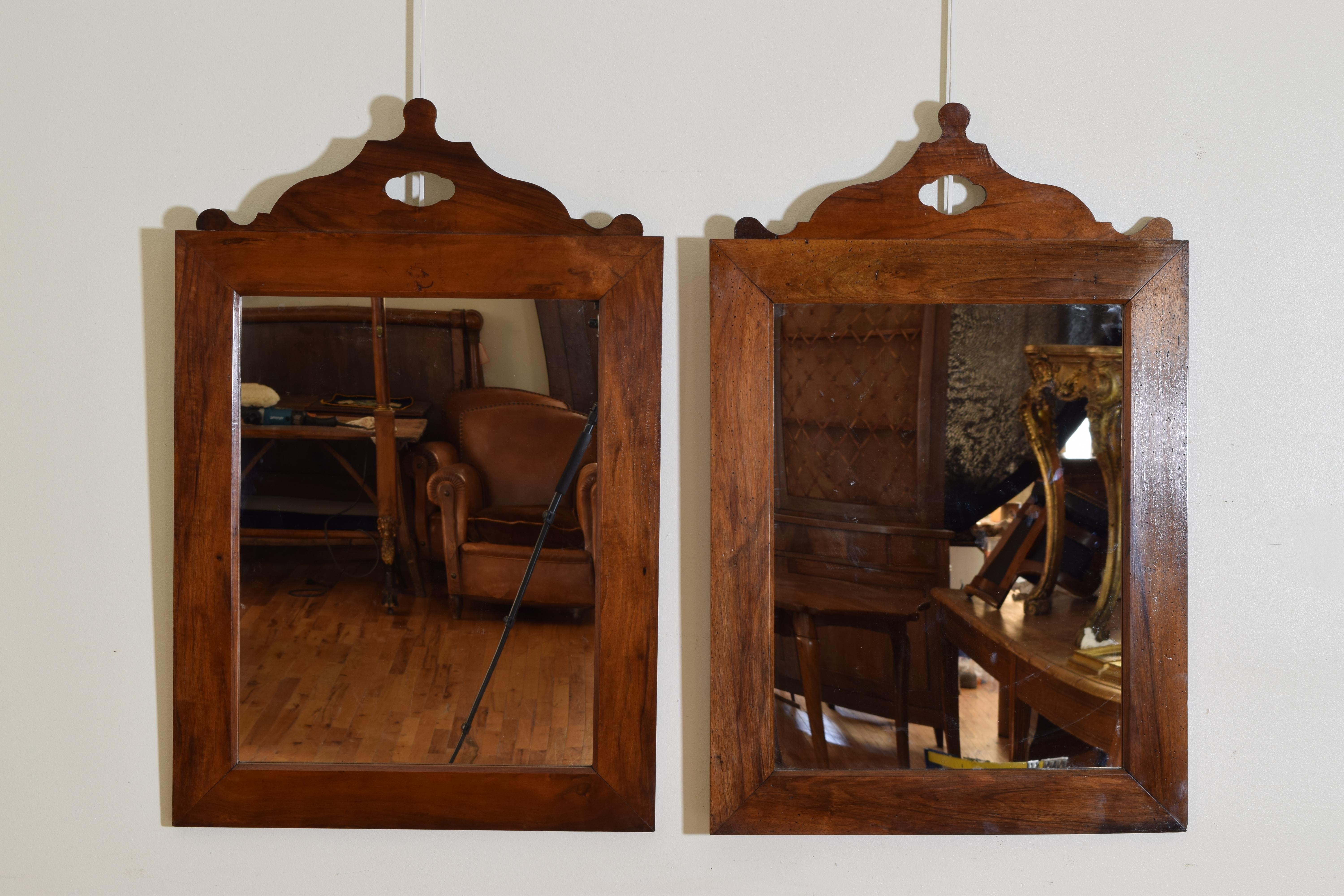 Constructed of solid walnut the rectangular frames surmounted by shaped tops, with new mirrorplates