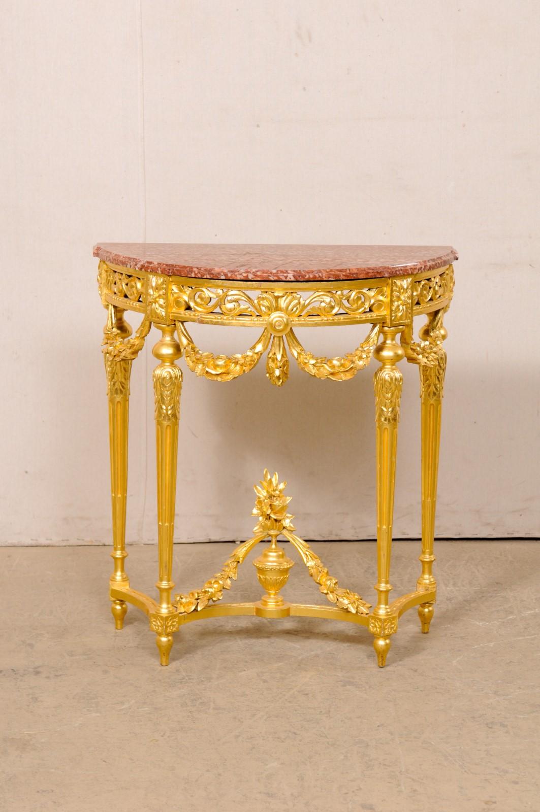A French Neoclassical petite console table, with marble top and carved urn finial accent at underside, from the 19th century. This antique table from France features a half-moon shaped marble top with flattened backside (so that it can rest