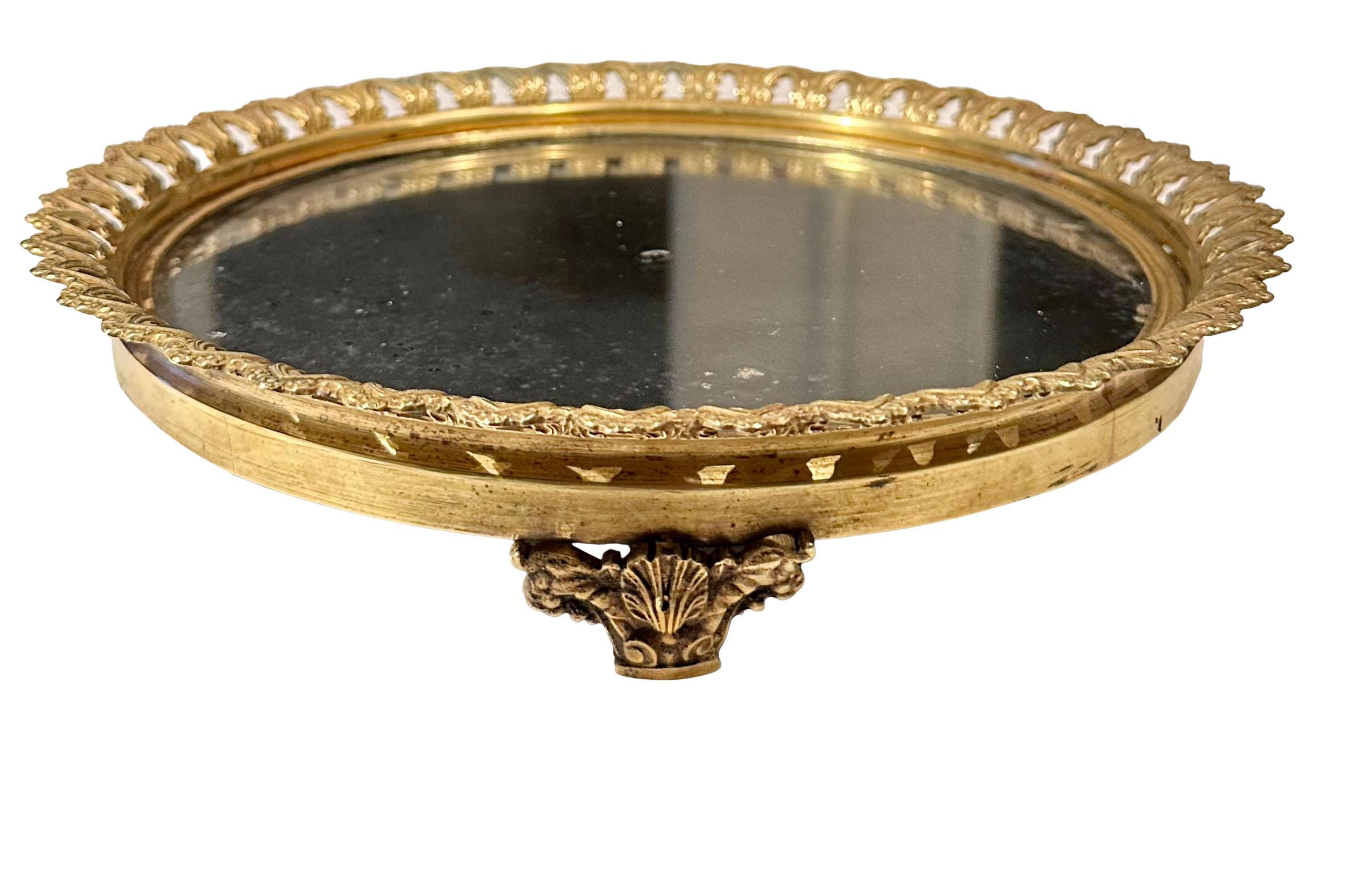 An early 19th century French neoclassical plateau with original glass and dore bronze with a beautiful reticulated edge and three shell feet surrounded by garlands. The mirror its self measure nine inches.