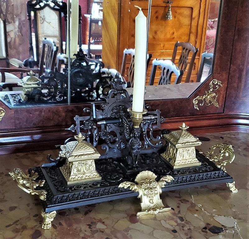 Lovely early 20th century French, neoclassical revival style pierced and cast bronze frieze and ormolu mounted gilt metal table or desk stand.

It has 2 gilt ormolu and hinged lidded inkwells (no glass), pen holders and a central candlestick,