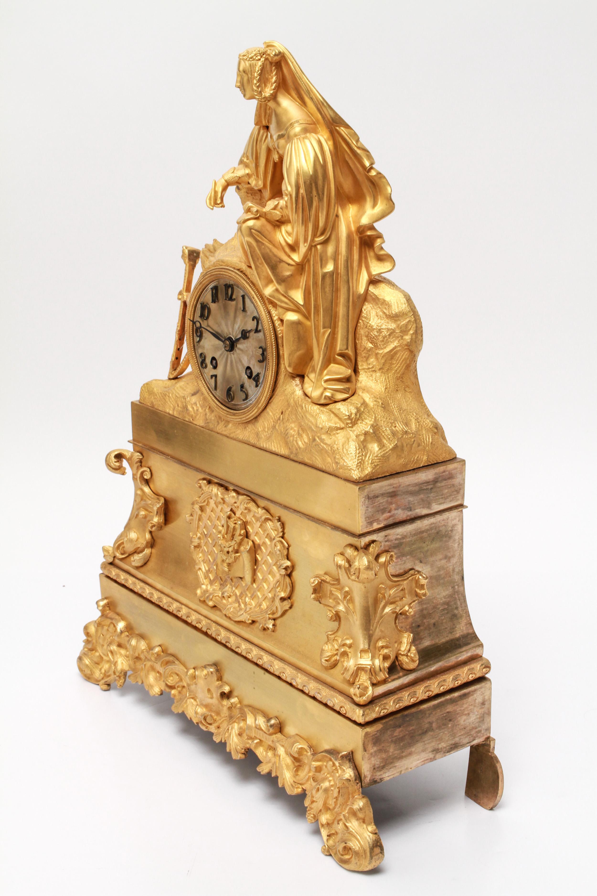 French neoclassical Revival gilt-bronze ormolu figural clock depicting a woman in fancy dress holding paper and pen with a propped hand-held harp. The piece has an engine-turned dial with applied Arabic numerals. Made during the 19th century. In