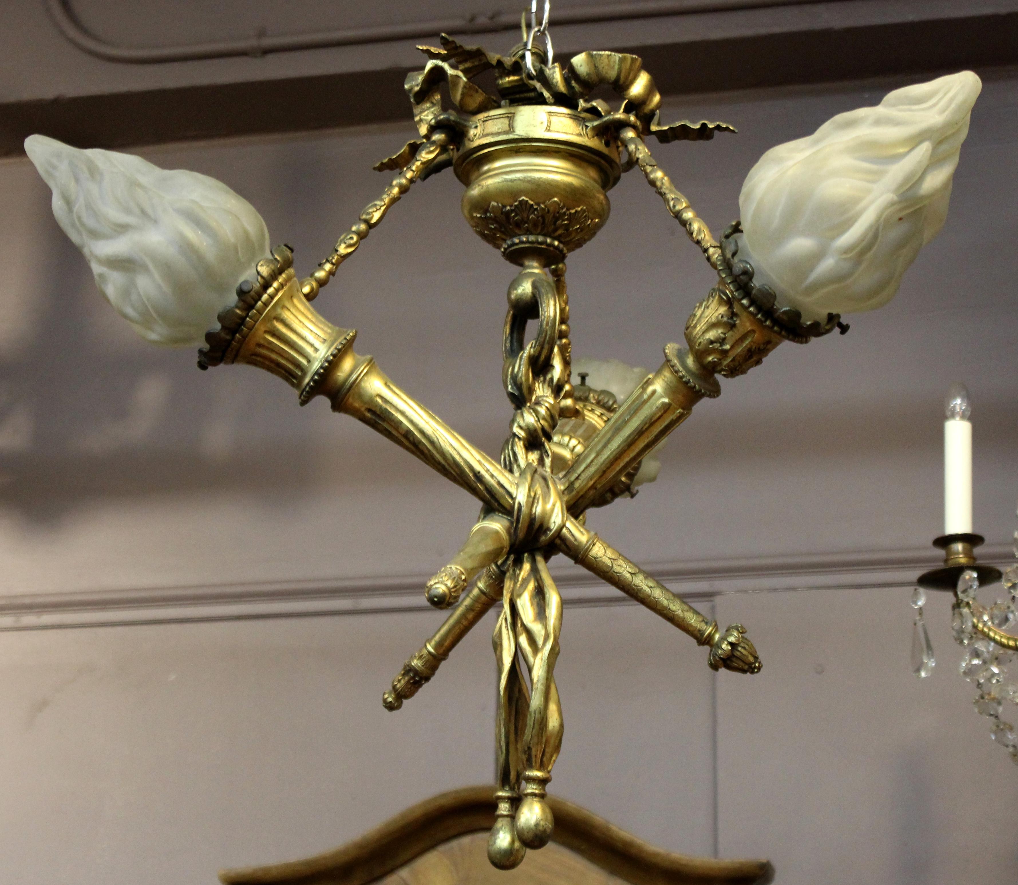 French neoclassical Revival gilt bronze pendant ceiling light with three bound torches with fire-shaped glass shades. The piece was made during the late 19th century and is in great vintage condition, with some age-appropriate wear and patina to the