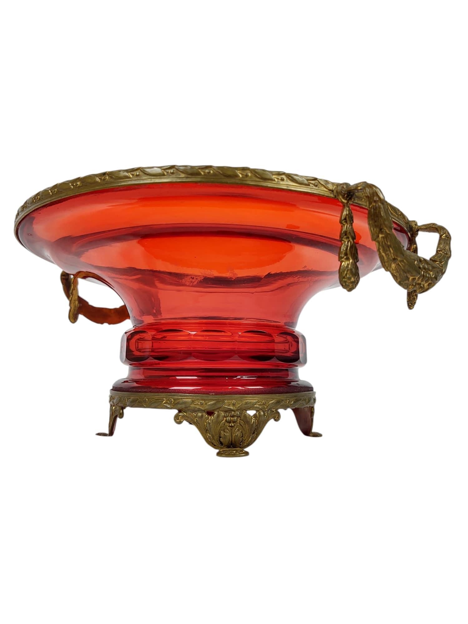 Cuenco neoclásico francés de vidrio rojo rubí, hacia finales del siglo XIX, inspirado en la grandeza de los periodos Imperio y Restauración. El vívido cristal rubí está encerrado en un borde, asas y base de bronce dorado finamente fundido, cada uno