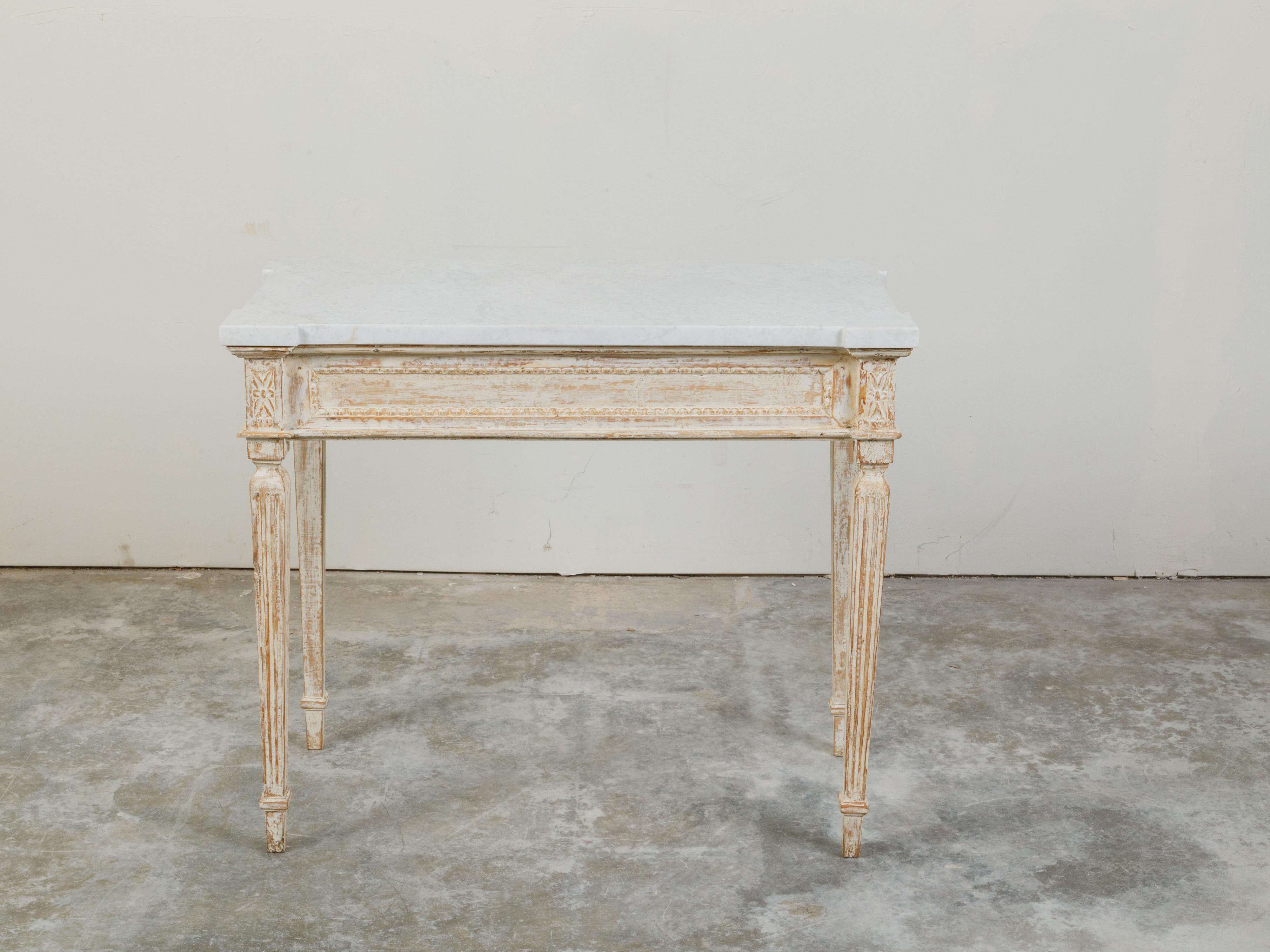 A French Neoclassical style painted wood console table from the 19th century, with white marble top and tapered legs. Created in France during the 19th century, this Neoclassical style table features a rectangular white marble top with protruding