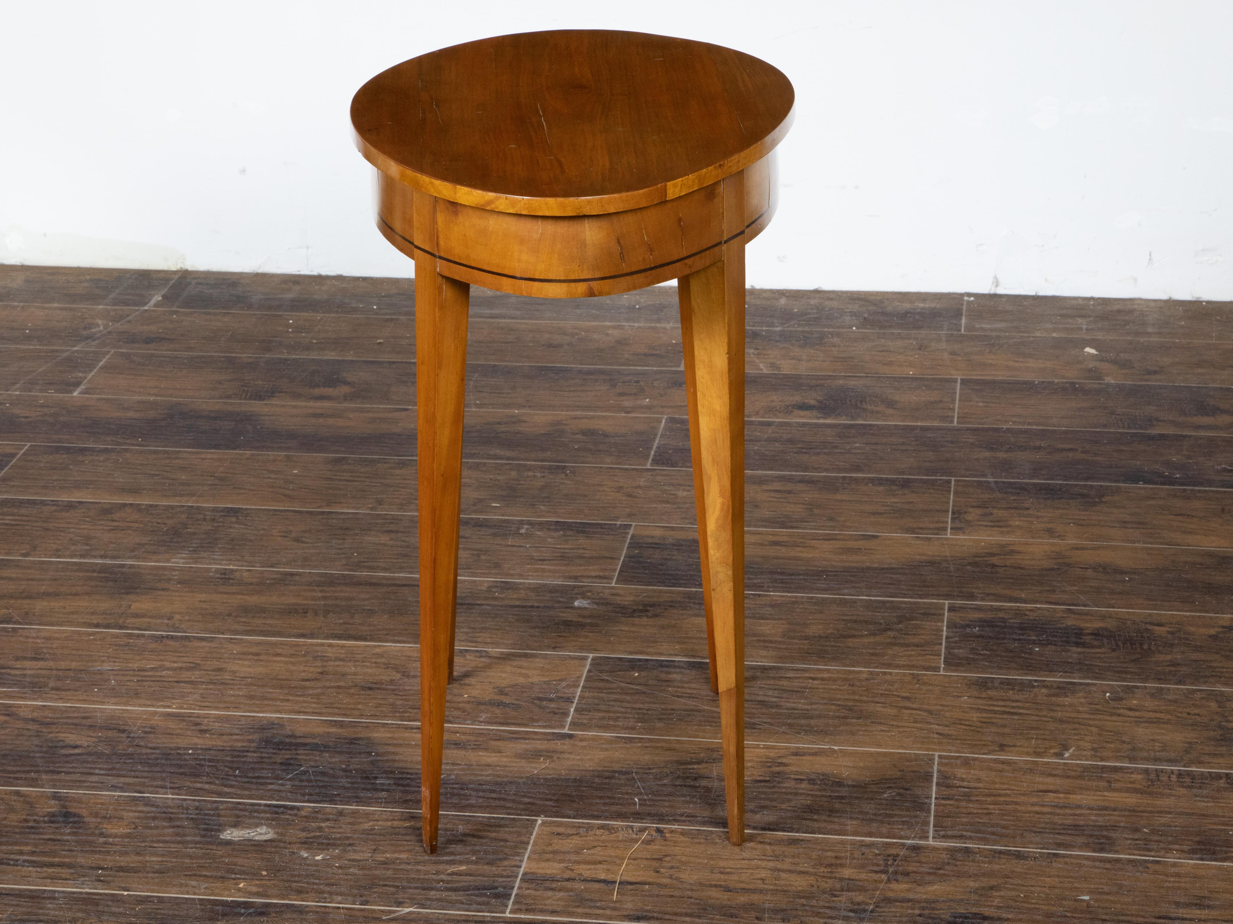 A French Neoclassical style walnut side table from the 19th century, with almond shaped top, ebonized accents and tapered legs. Created in France during the 19th century, this walnut veneered side table features an unusual almond shaped top sitting