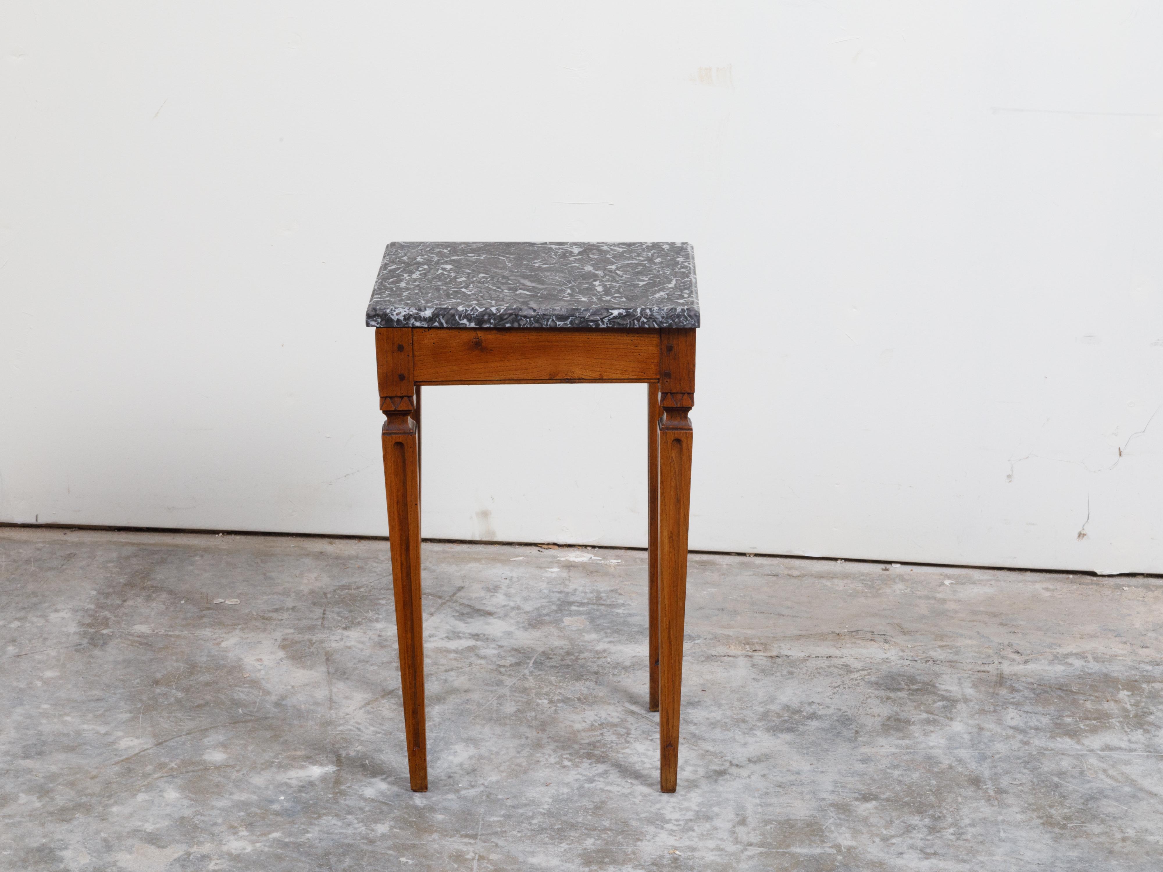 A French Neoclassical style wooden side table from the 19th century, with grey marble top and fluted legs. Created in France during the 19th century, this side table features a rectangular grey veined marble top sitting above an apron carved with