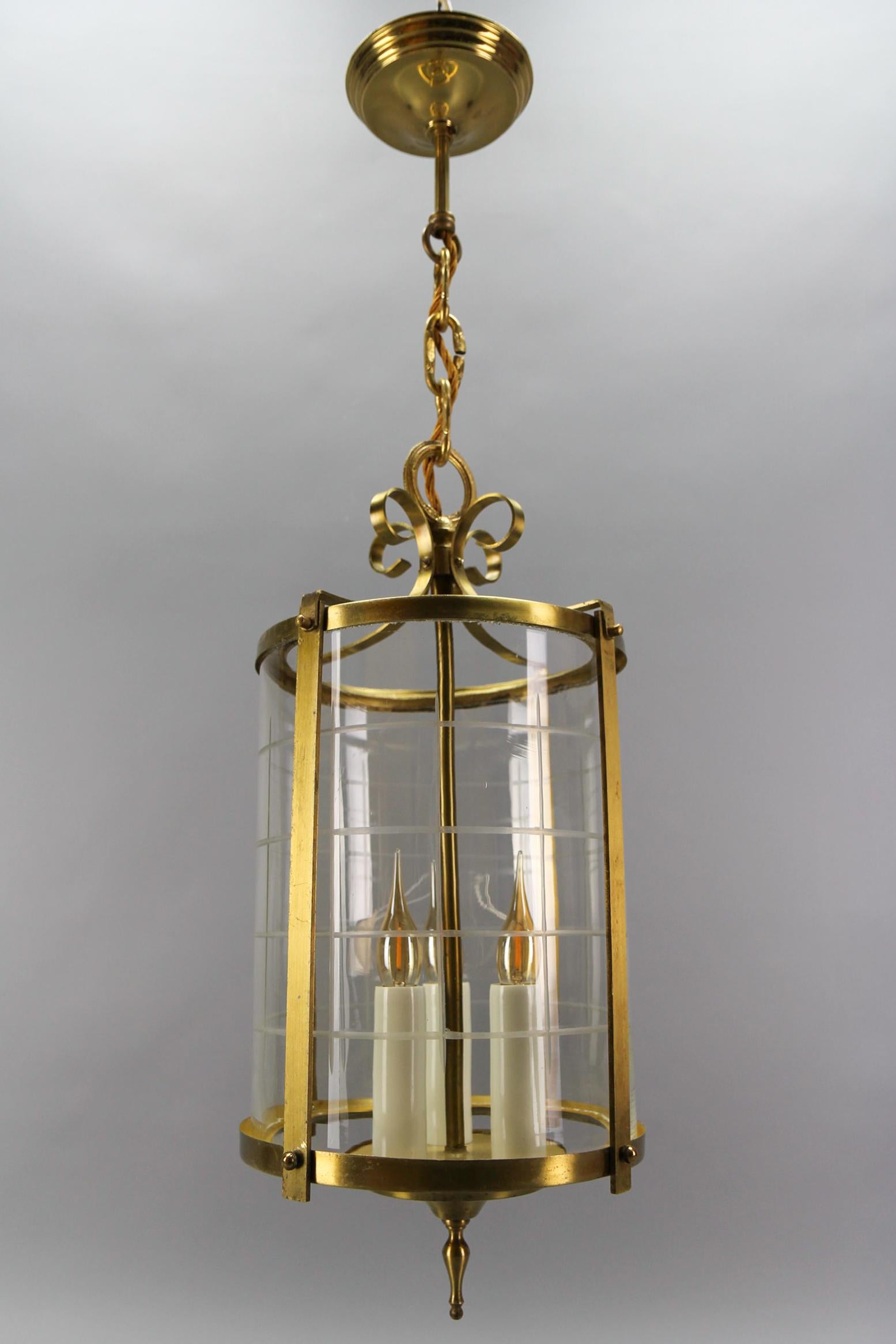Lanterne ronde suspendue en laiton et verre clair taillé, datant des années 1920.
Cette adorable lanterne suspendue antique à trois lumières est dotée d'un élégant cadre rond en laiton et d'un verre rond et transparent taillé.
Trois douilles pour
