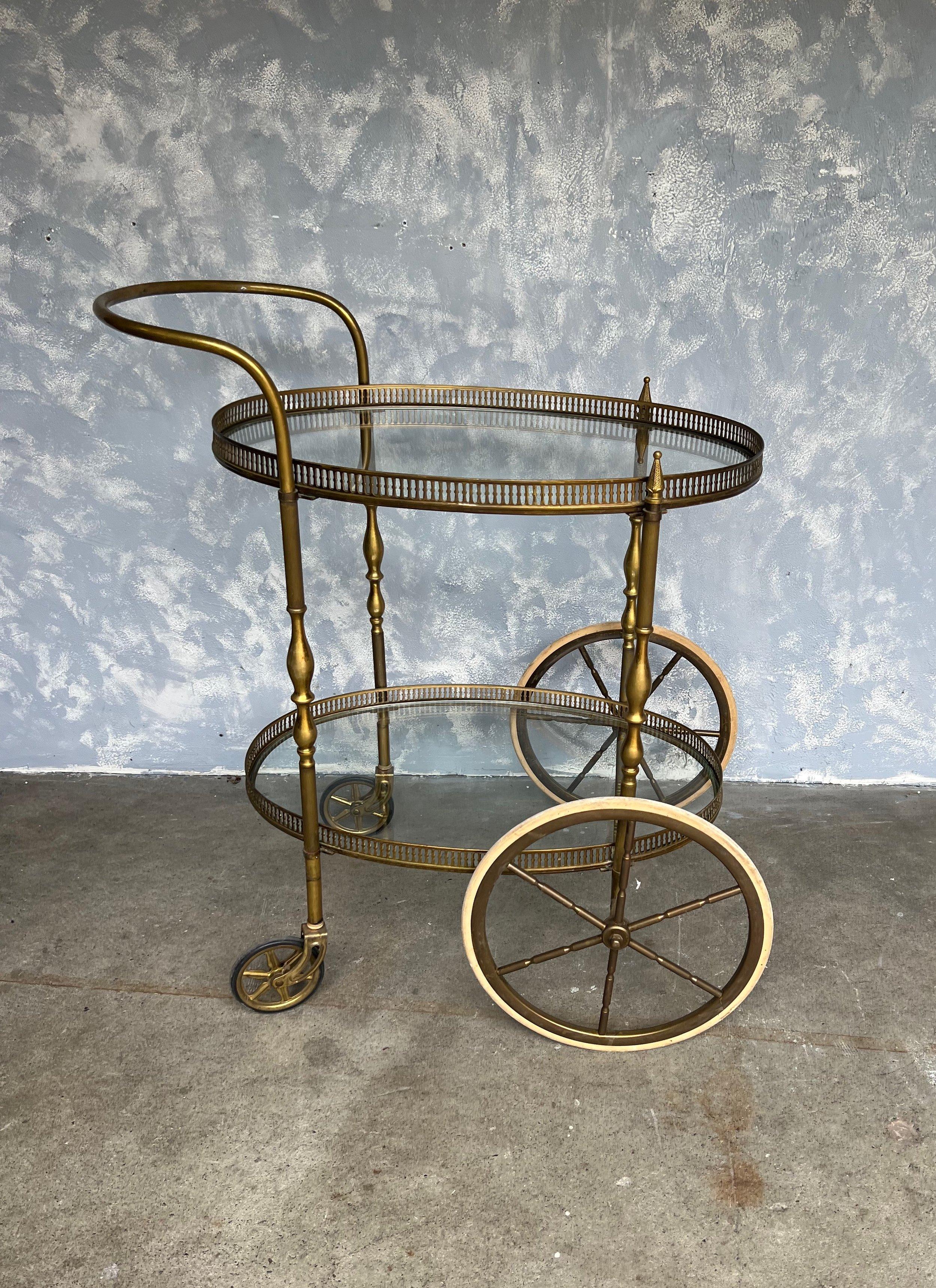 A handsome French bar cart from the 1940s having a brass frame and 2 oval shaped glass shelves enclosed in a brass gallery. The bar cart is mounted on casters making it easy to move around. Very good vintage condition.

Ref #: