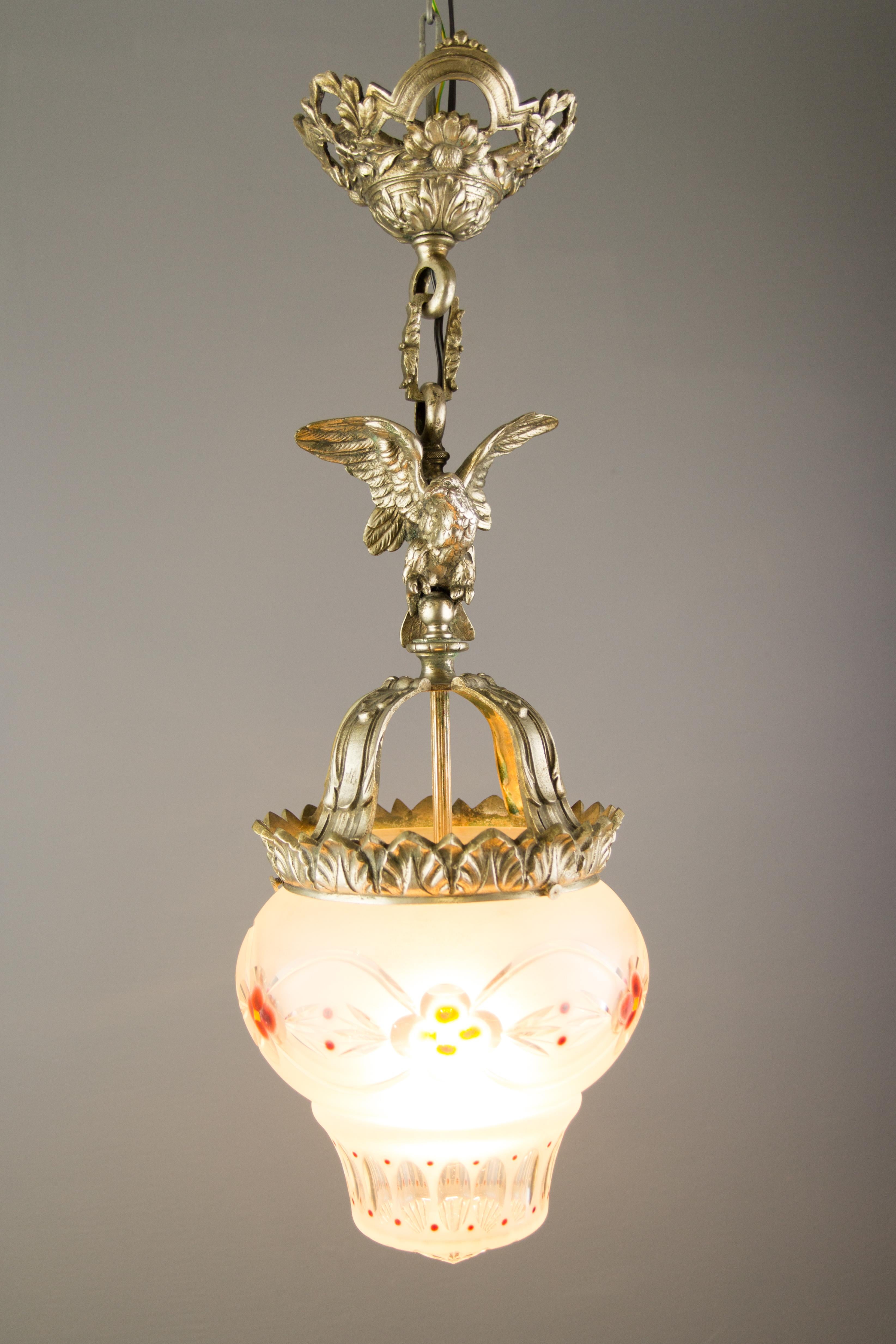 French Neoclassical style bronze and frosted glass pendant light with an eagle from circa the 1920s.
A decorative French pendant light made of bronze with a spread-winged eagle above the bronze crown. Beautifully shaped, engraved frosted glass