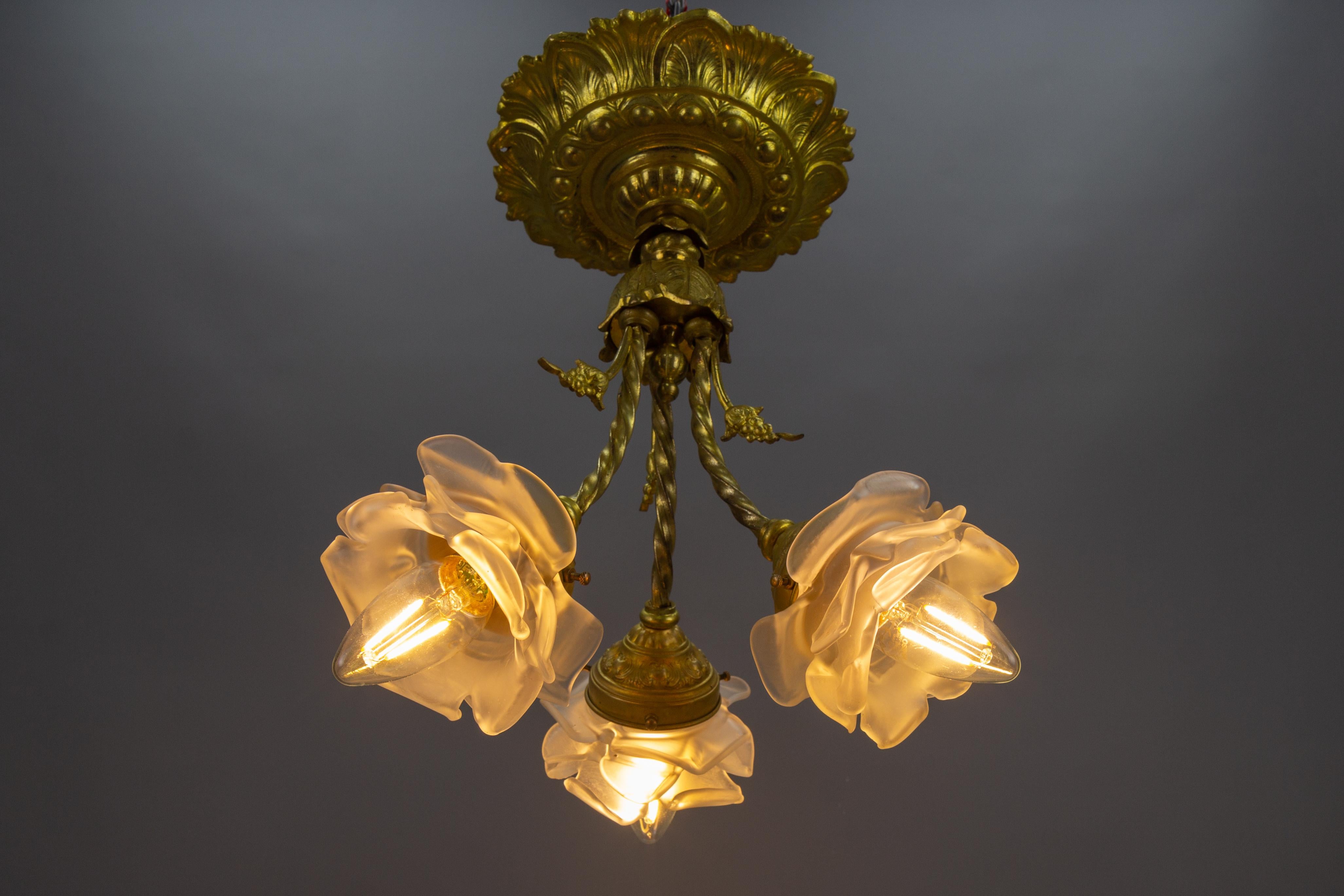 French Neoclassical style bronze, brass, and glass ceiling light fixture, from circa the 1920s.
This adorable Neoclassical style three-light ceiling lamp features an impressive and ornate ceiling canopy, three arms each with a flower-shaped glass