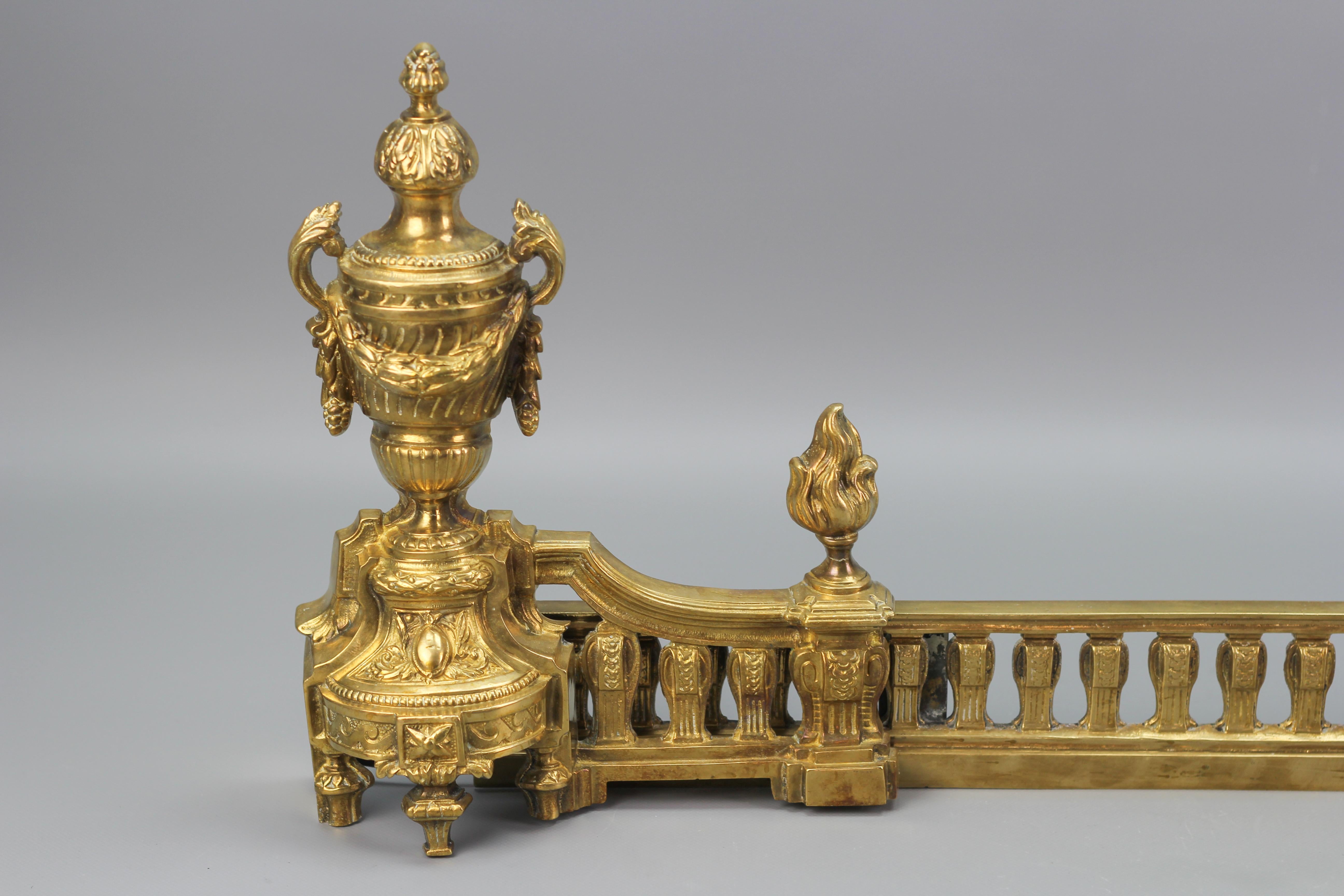 French Neoclassical style bronze fireplace fender set, late 19th century, sold as a set of 3.
This impressive French Neoclassical style bronze fender set dates to the late 1800s. Richly ornate with acanthus foliate accents, urns, and flame