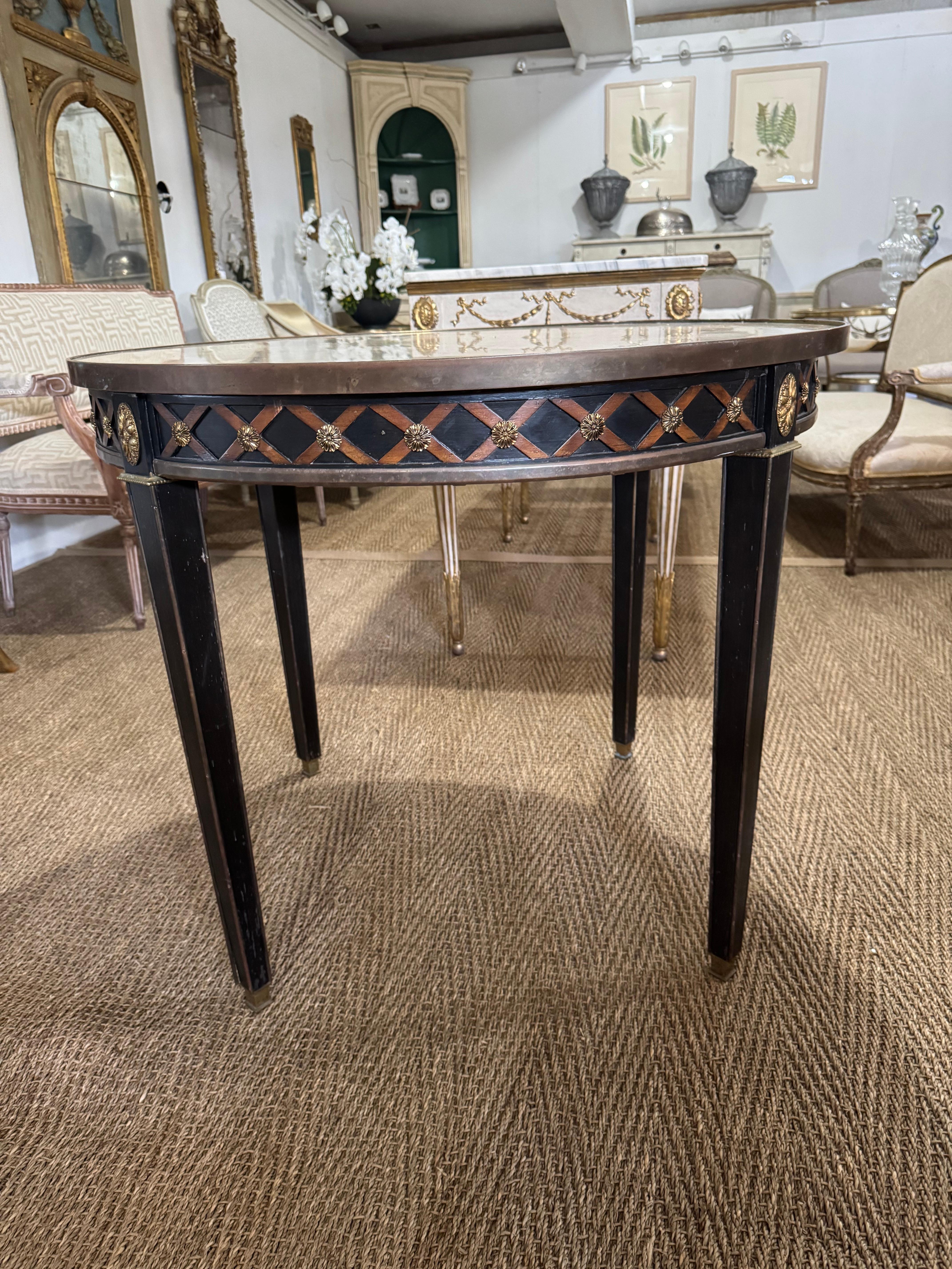 Table circulaire de style néoclassique français, peinte en noir, avec un plateau en marbre beige veiné, une garniture à bandes croisées en laiton et un décor détaillé de rosettes en laiton à l'intérieur de chaque bande croisée, ainsi qu'un décor de