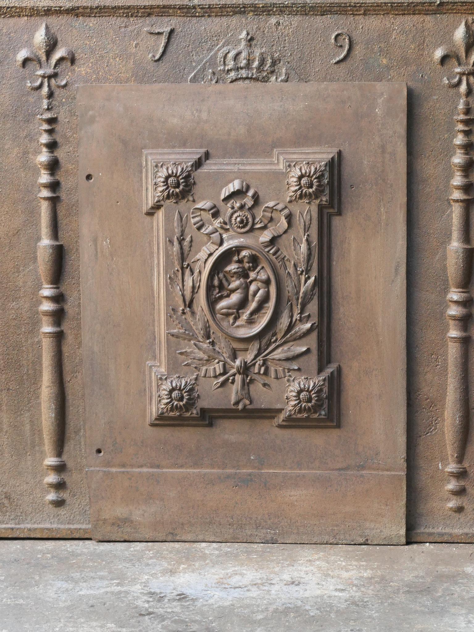 Plaque de cheminée de style néoclassique français avec des cupidons entourés d'autres décorations. La plaque de cheminée est en fonte et a une patine brune naturelle. Sur demande, il peut être de couleur noire. L'état est bon, pas de