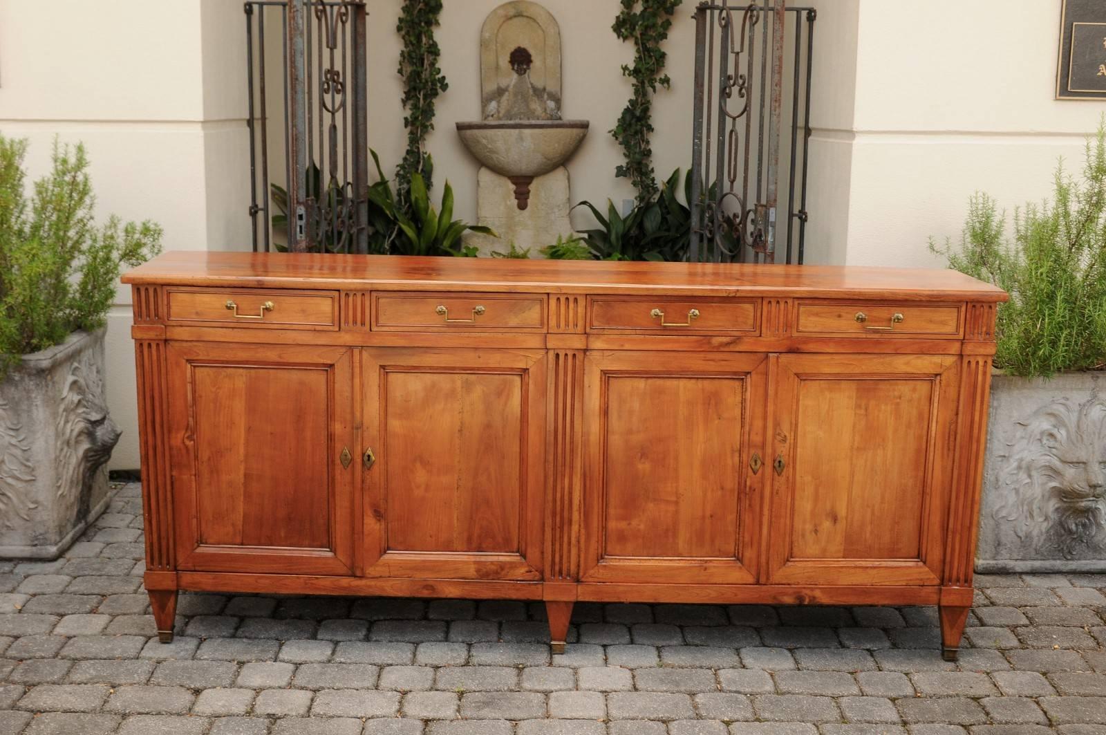 A French neoclassical style fruitwood enfilade from the second half of the 19th century, with four drawers over four doors and fluted accents. This exquisite French enfilade features a rectangular top, sitting above four drawers, adorned with linear