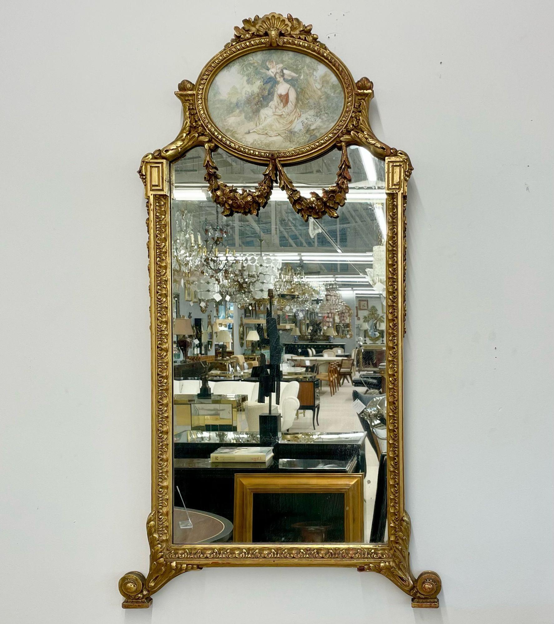 Miroir mural / console en bois doré de style néoclassique français avec une œuvre d'art ovale représentant une jeune fille et son chérubin. 
Miroir mural finement moulé en gesso doré. Diminutif dans sa forme, avec un cadre sculpté et éclairé par un