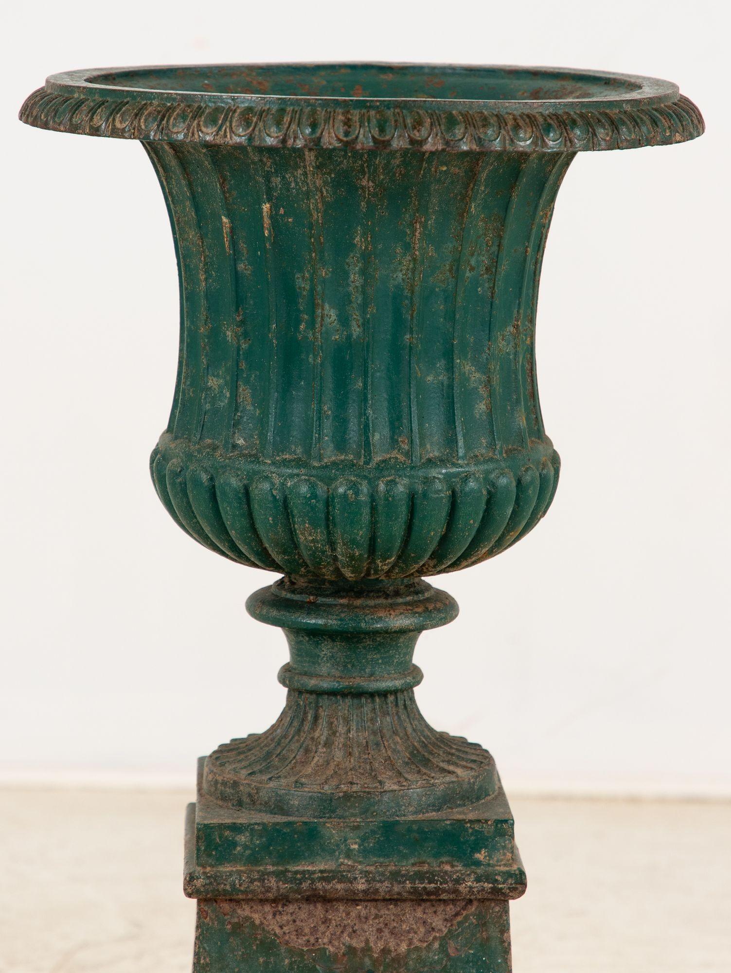 Une urne en fonte de style néoclassique français sur pied, datant du milieu du 20e siècle. Dotée de proportions élégantes et d'un design intemporel, l'urne est recouverte d'une peinture verte qui rehausse son attrait classique. La pièce présente une