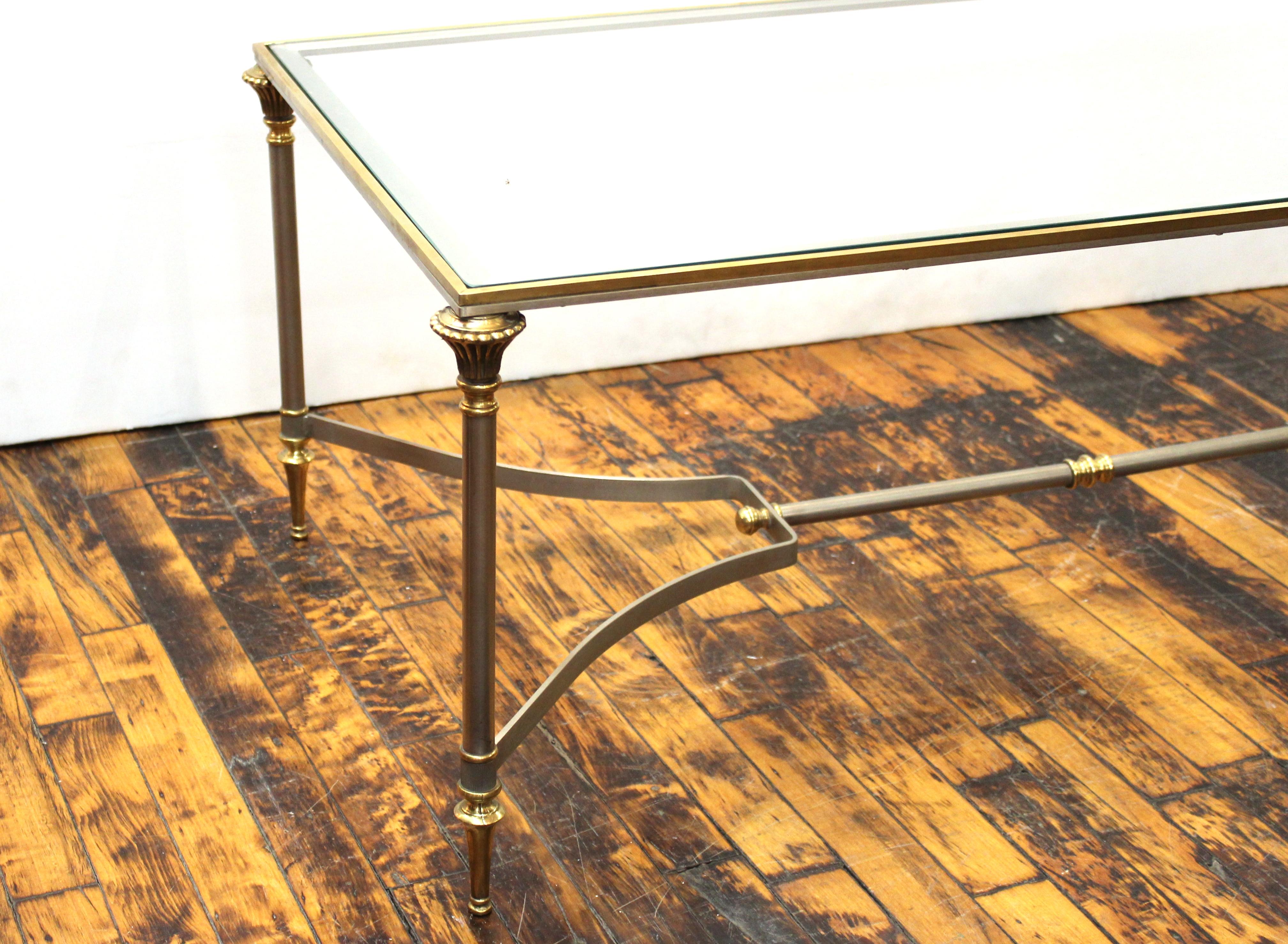 French Neoclassical style Maison Jansen coffee table with stretcher underneath and heavy glass top, made in France during the 1940s, in very good condition with age-appropriate wear and use.