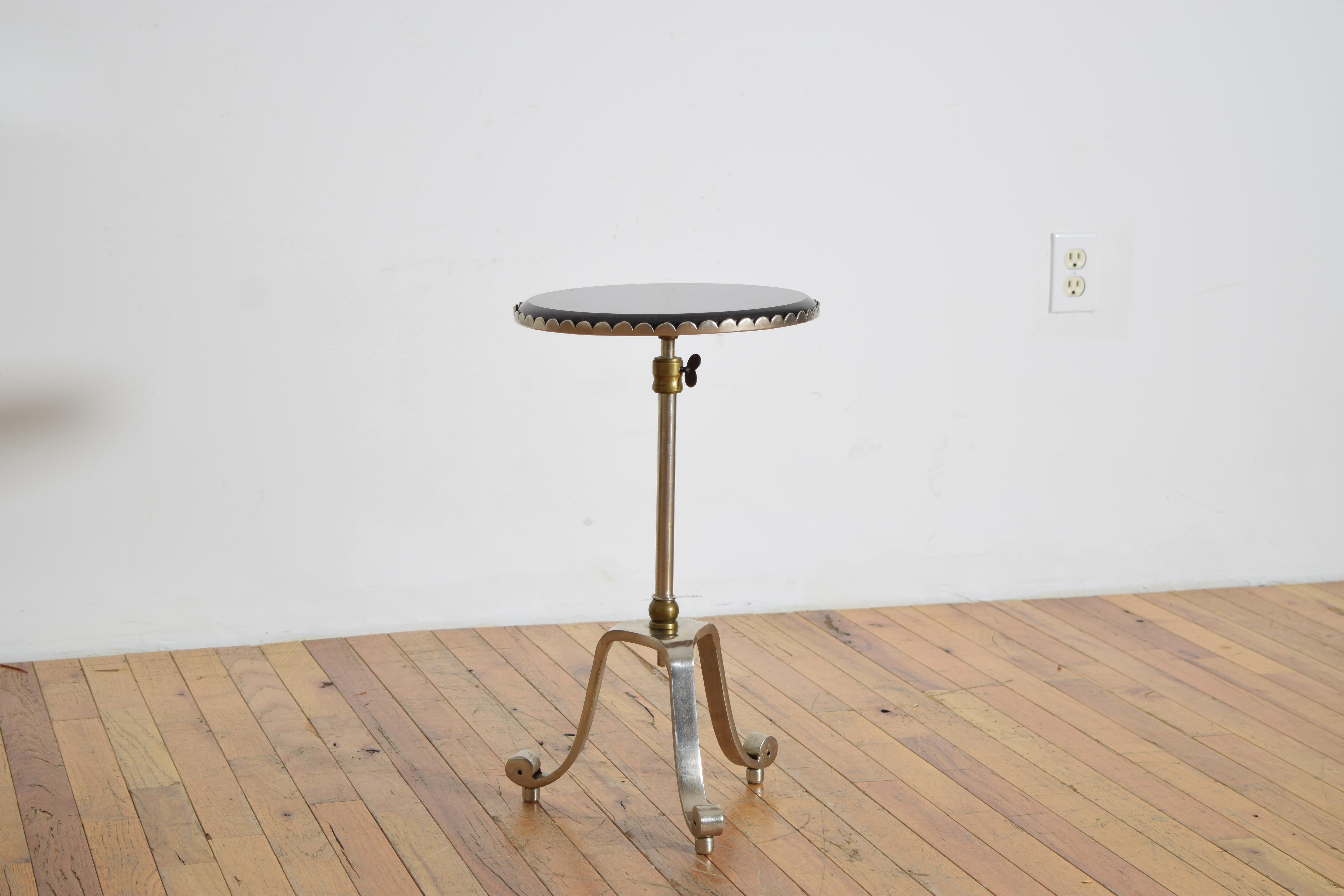 a petite drinks table in steel and brass, with a round polished granite top and scalloped edge