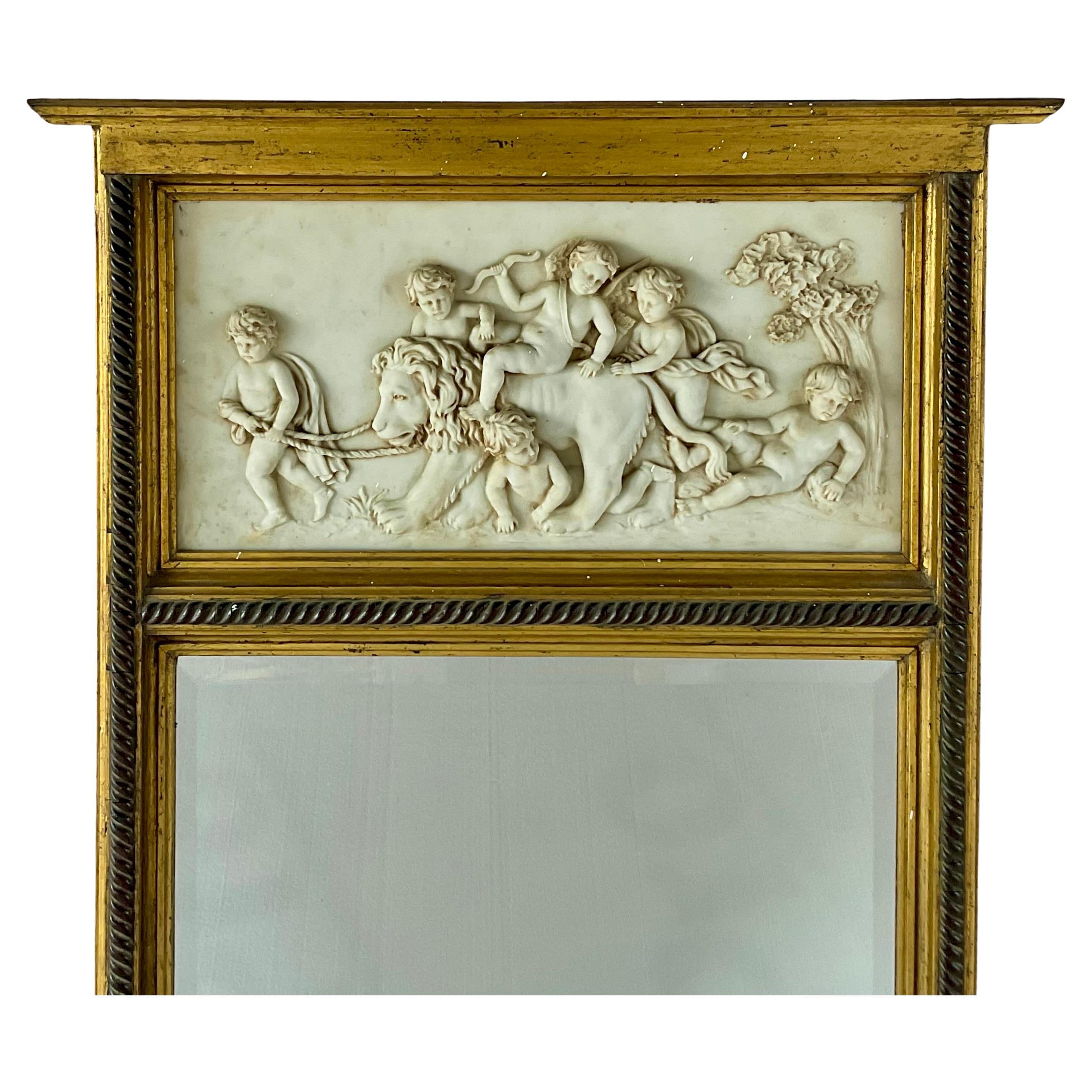 Miroir Trumeau en bois doré de style néoclassique français avec relief de chérubin. Le miroir présente un relief magnifiquement détaillé de chérubins enjoués et d'un lion dans un paysage pastoral. Le cadre en bois doré est orné d'une moulure en